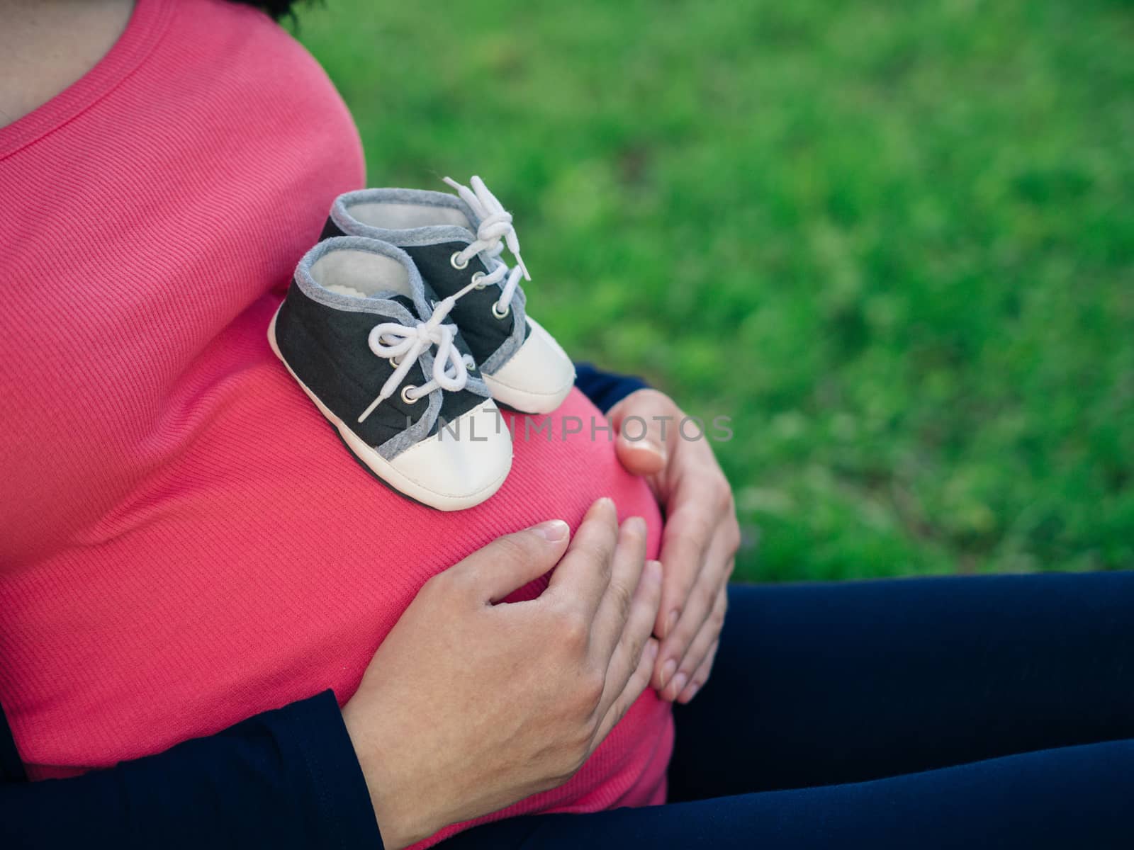 little shoes at pregnant belly close up by fascinadora