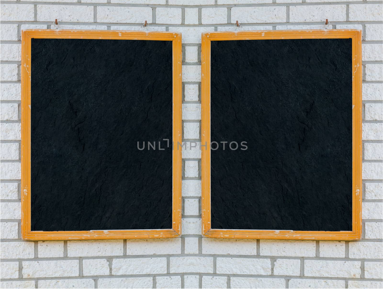 Two empty large slate boards with wooden frame on a stone wall.