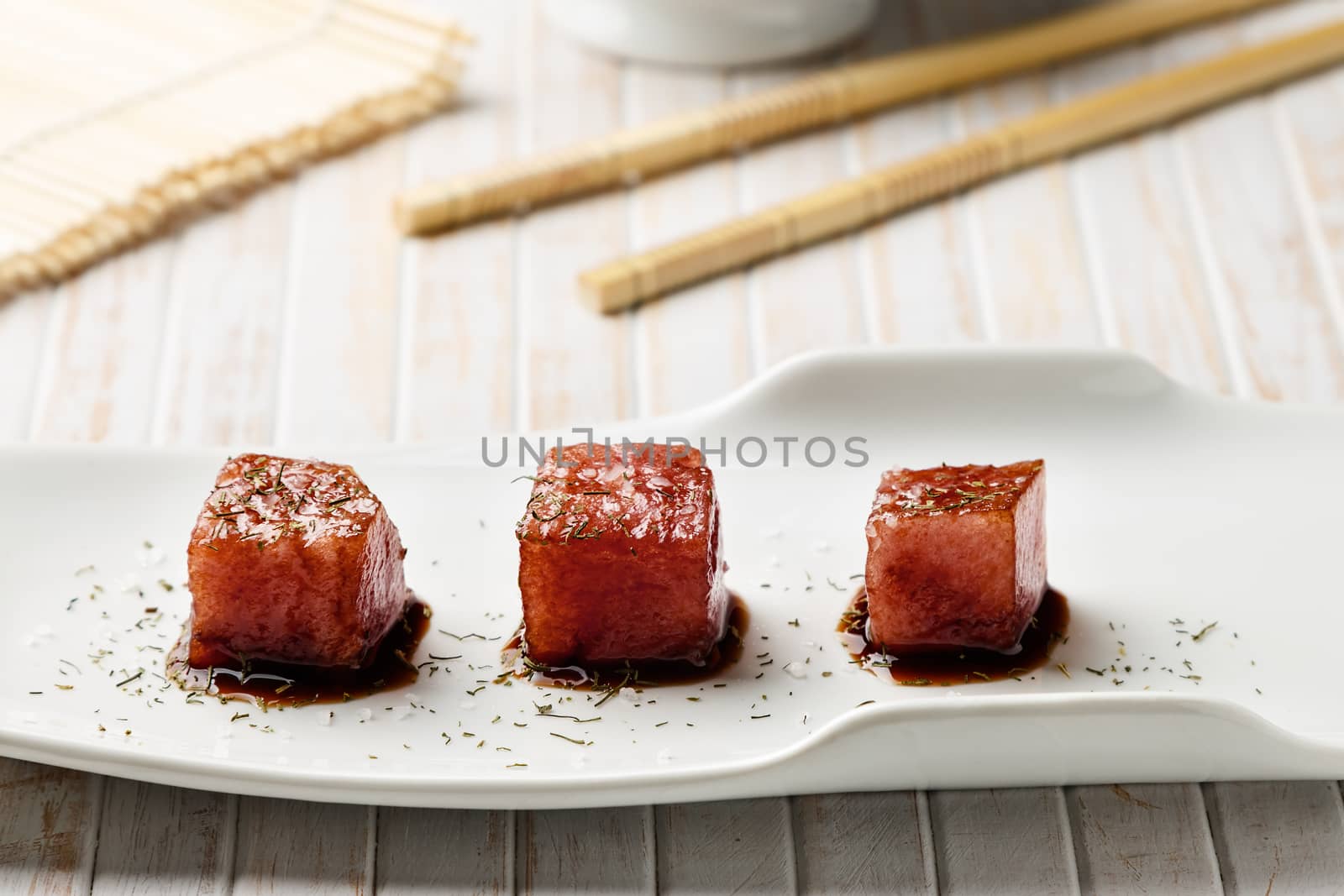 Tuna sashimi dipped in soy sauce,  thick salt and dill with chopsticks and bamboo mat. Raw fish in traditional Japanese style. Horizontal image.