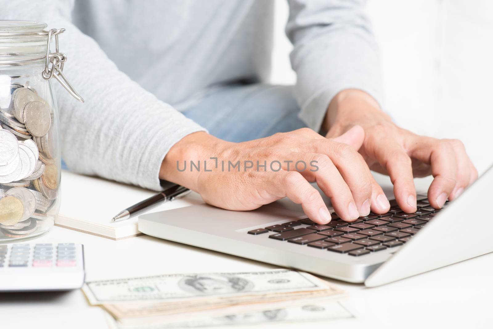 Man doing online trading, with laptop computer, calculator, diary, money on table. Accounting and technology. 