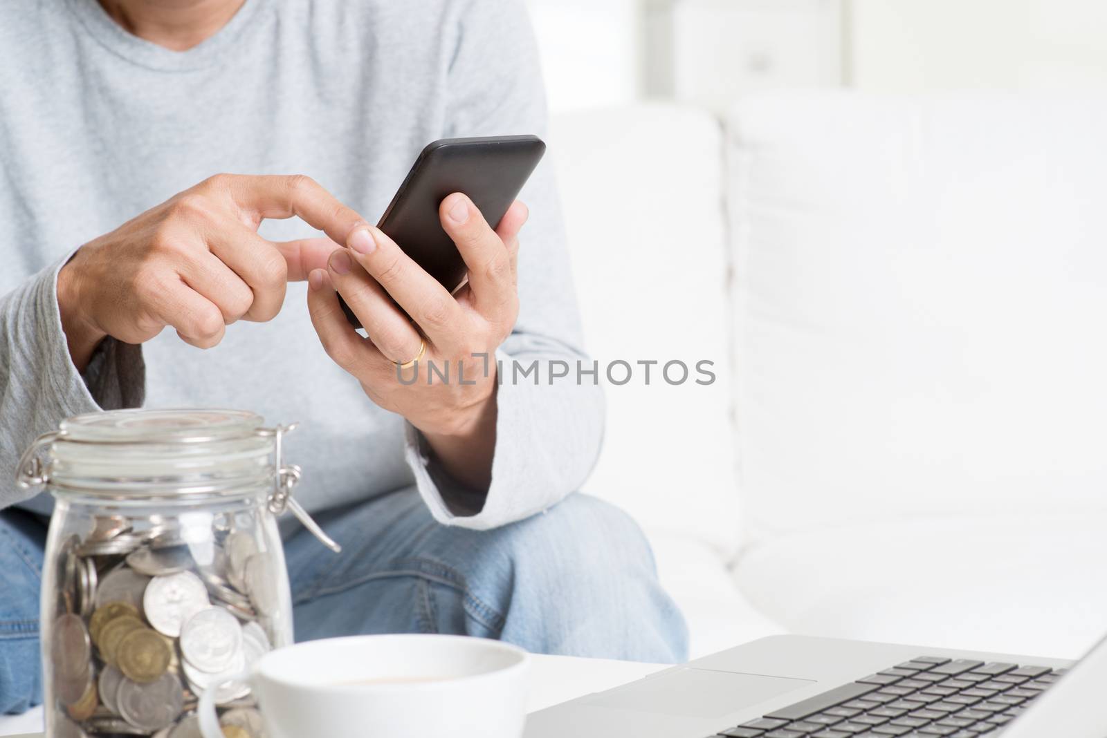Man doing online business, with smartphone and laptop computer at indoor home.