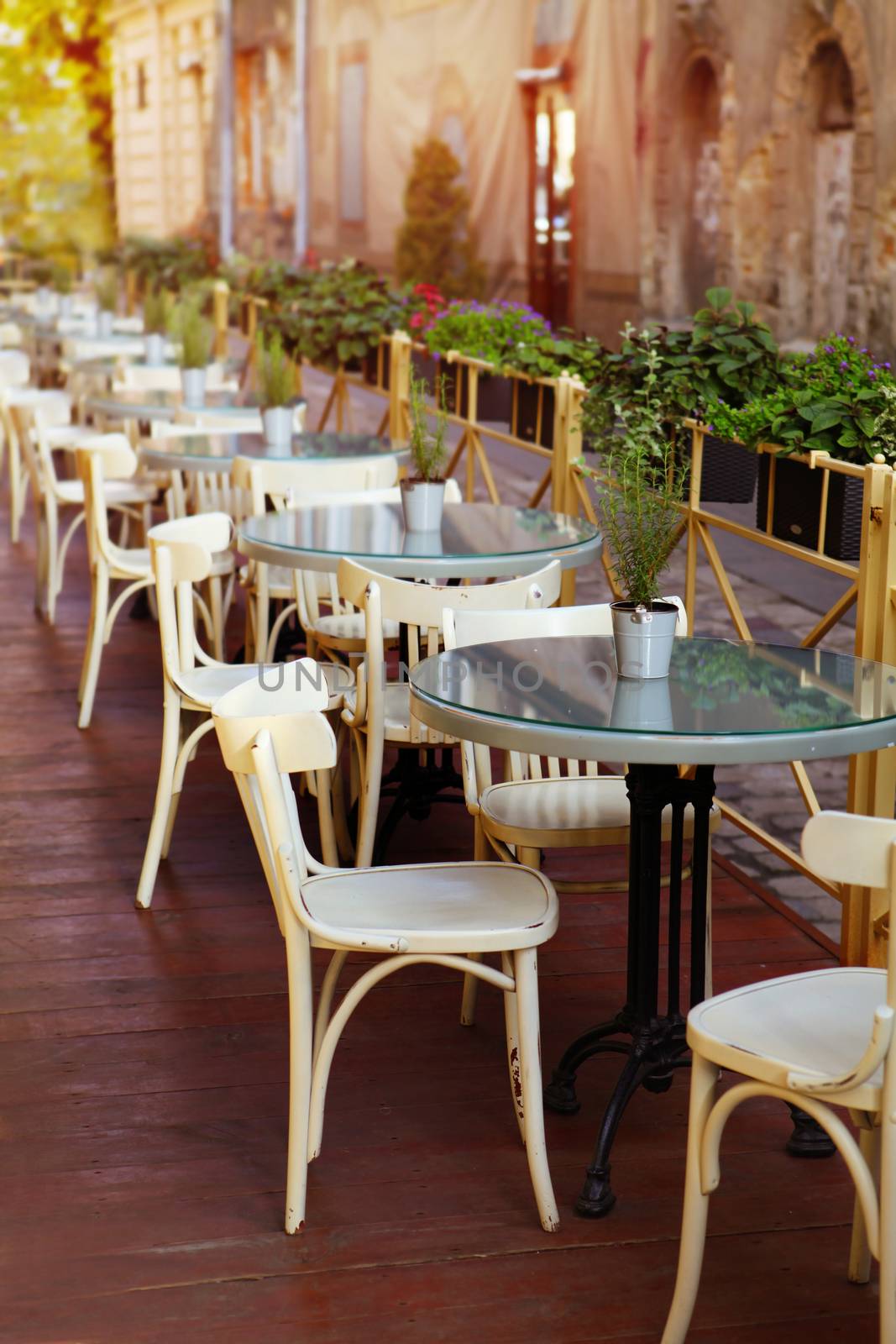 empty little white tables of cafeteria on the street at sun day