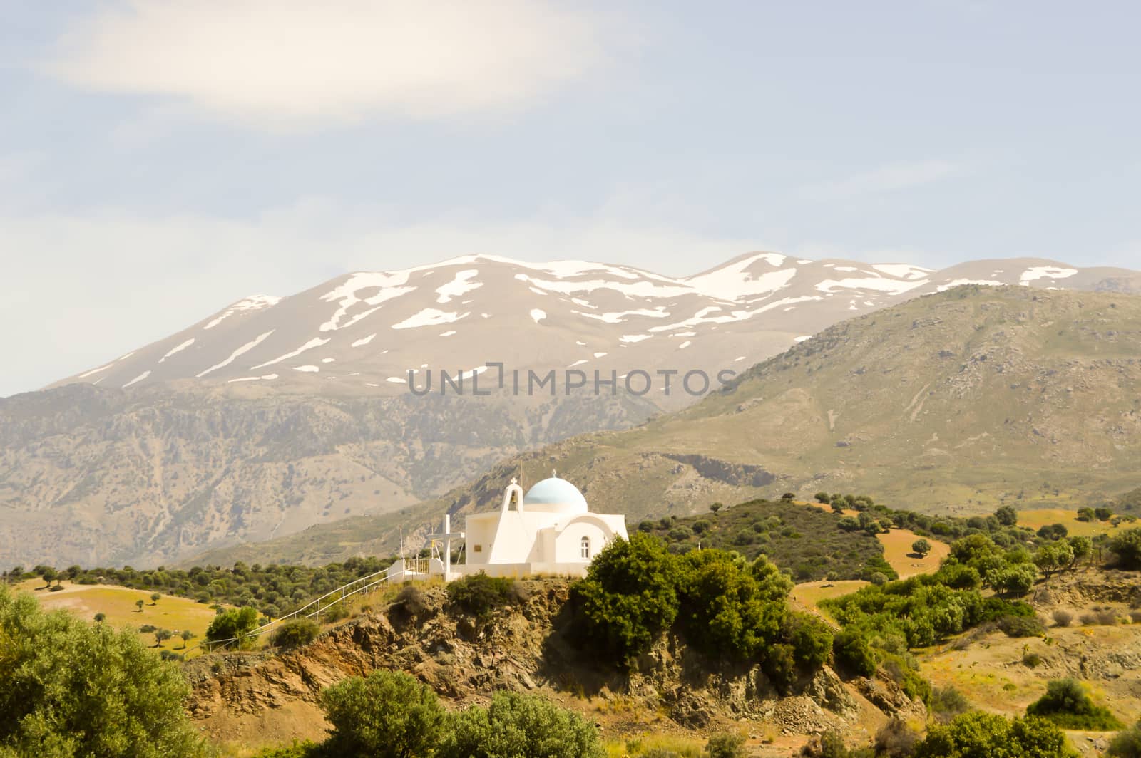 Orthodox church blue and white on a hill with psilotoris in the background