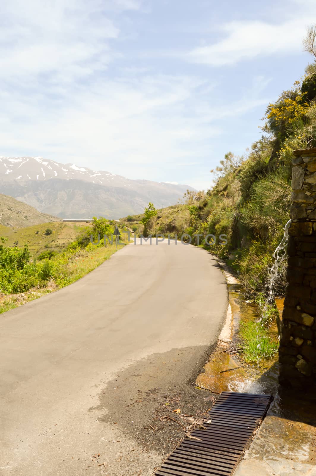 Small mountain road with a waterfall and the psilotoris in the background