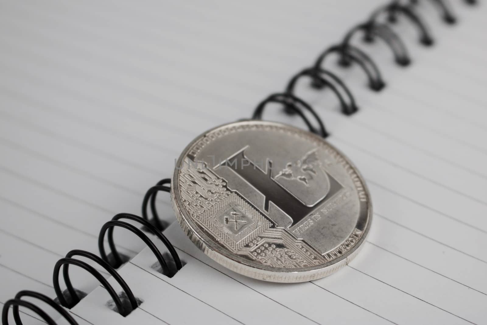 Cryptocurrency physical silver litecoin coin in notebook.