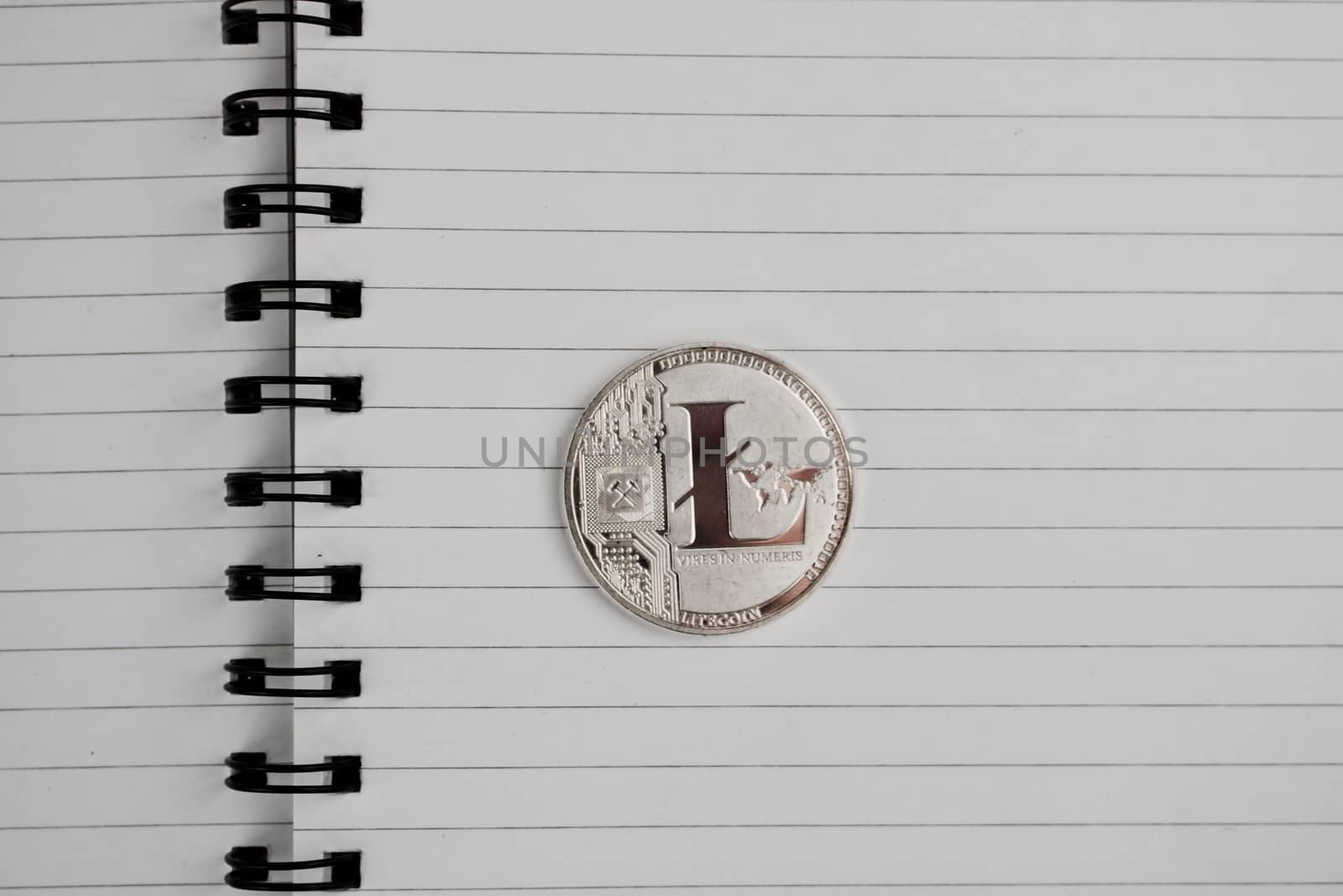 Cryptocurrency physical silver Litecoin coin in notebook.