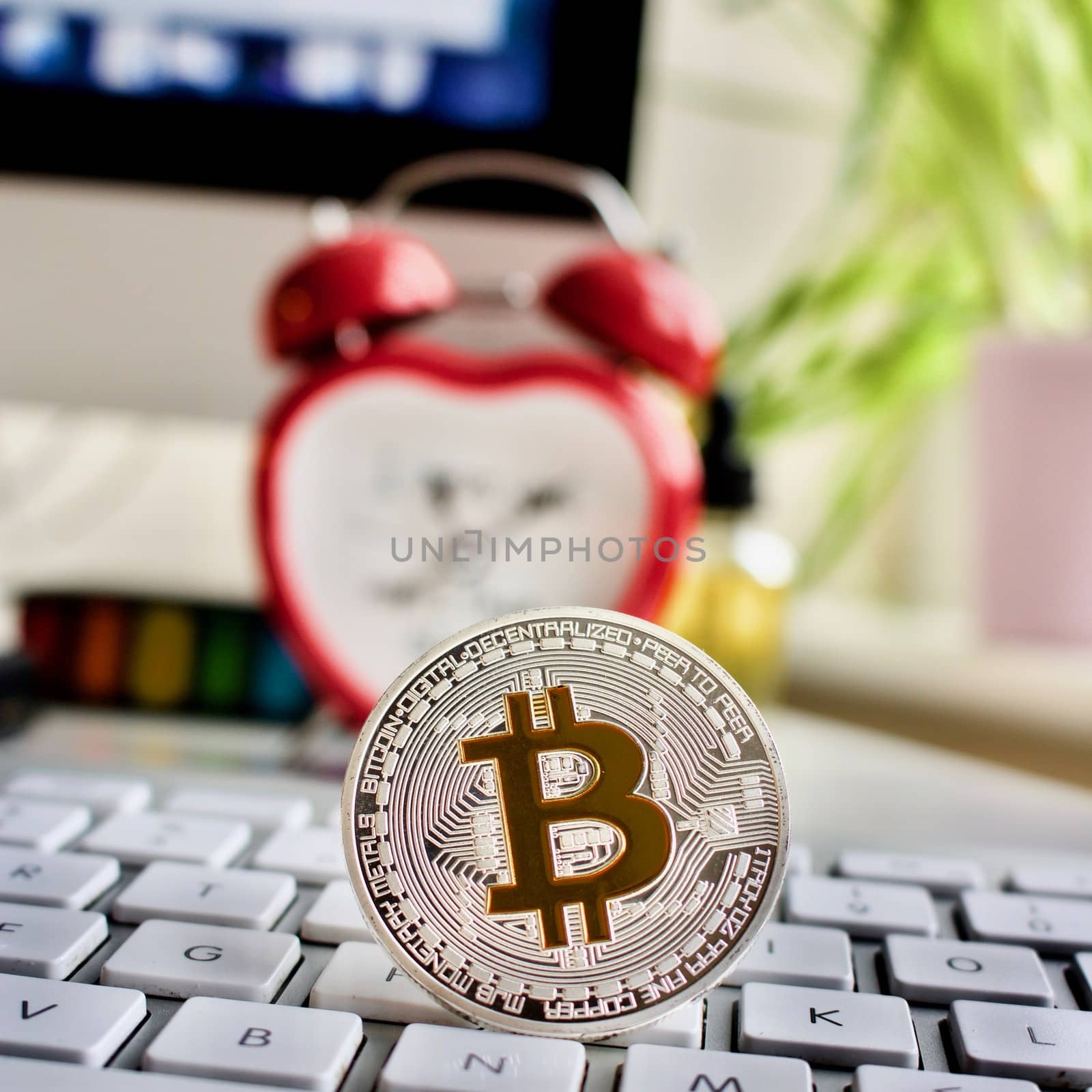 Cryptocurrency physical silver bitcoin coin, keyboard, screen and clock.