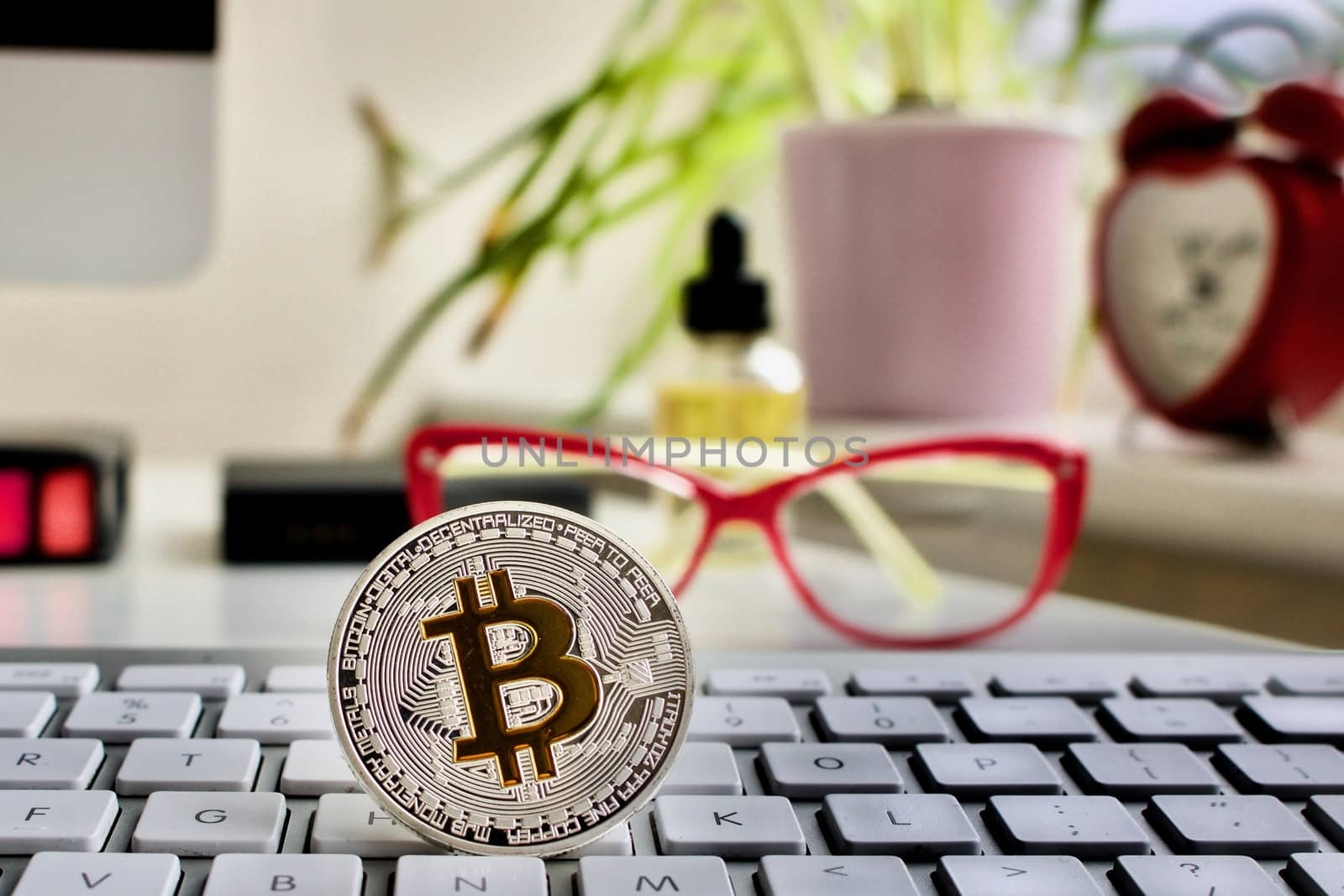 Cryptocurrency physical silver bitcoin coin. Pink glasses. Red clock and green plants.