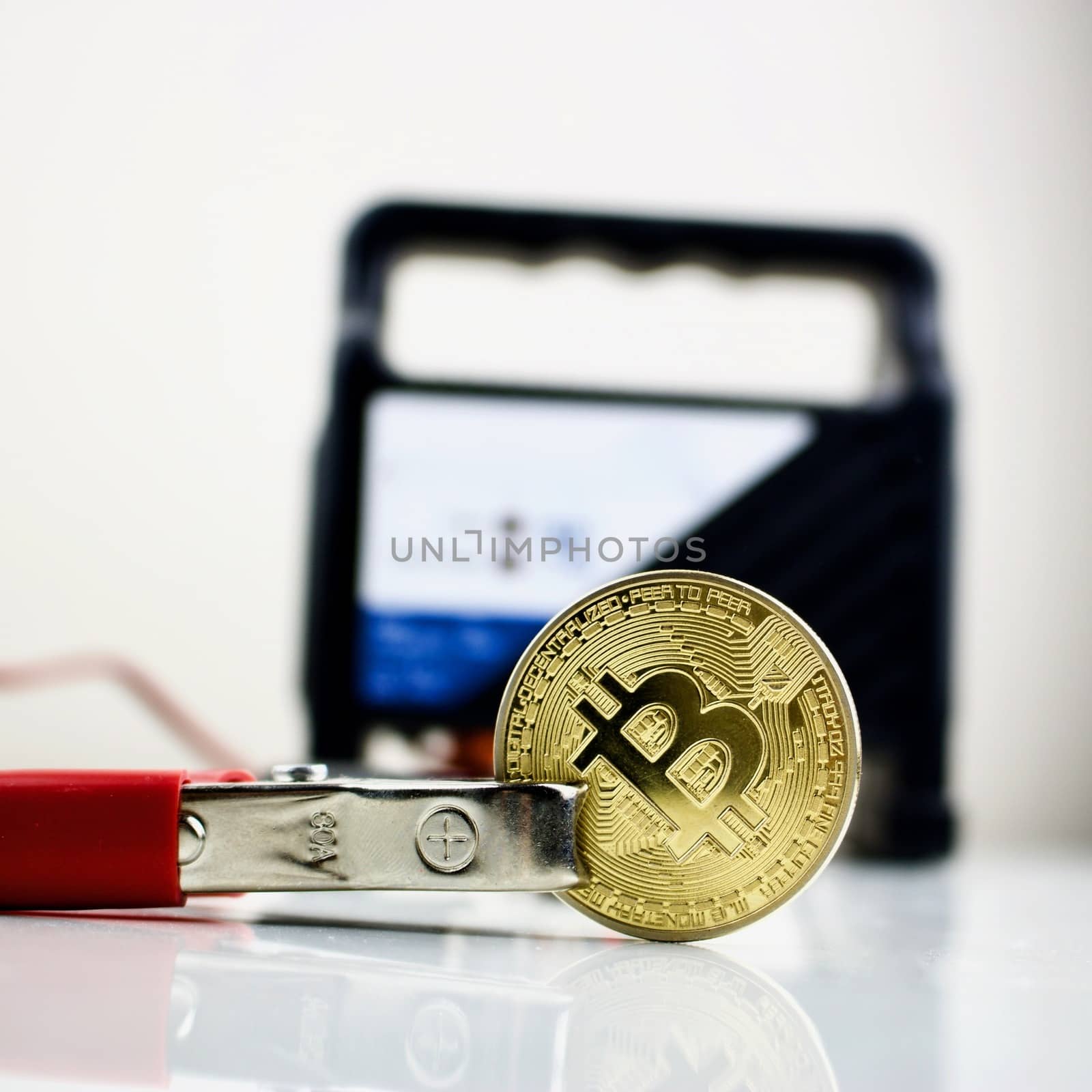 Black car charger connected with bitcoin gold cryptocurrency coin.