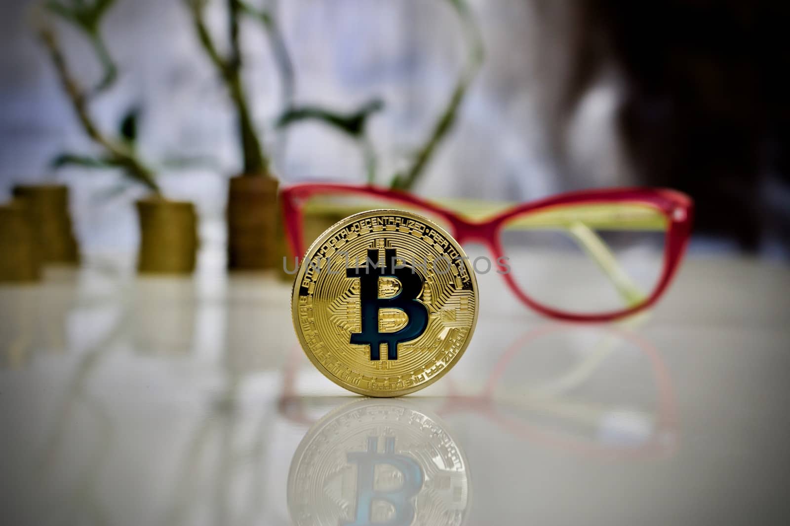 Digital currency physical gold bitcoin coin with blue sign near pink glasses