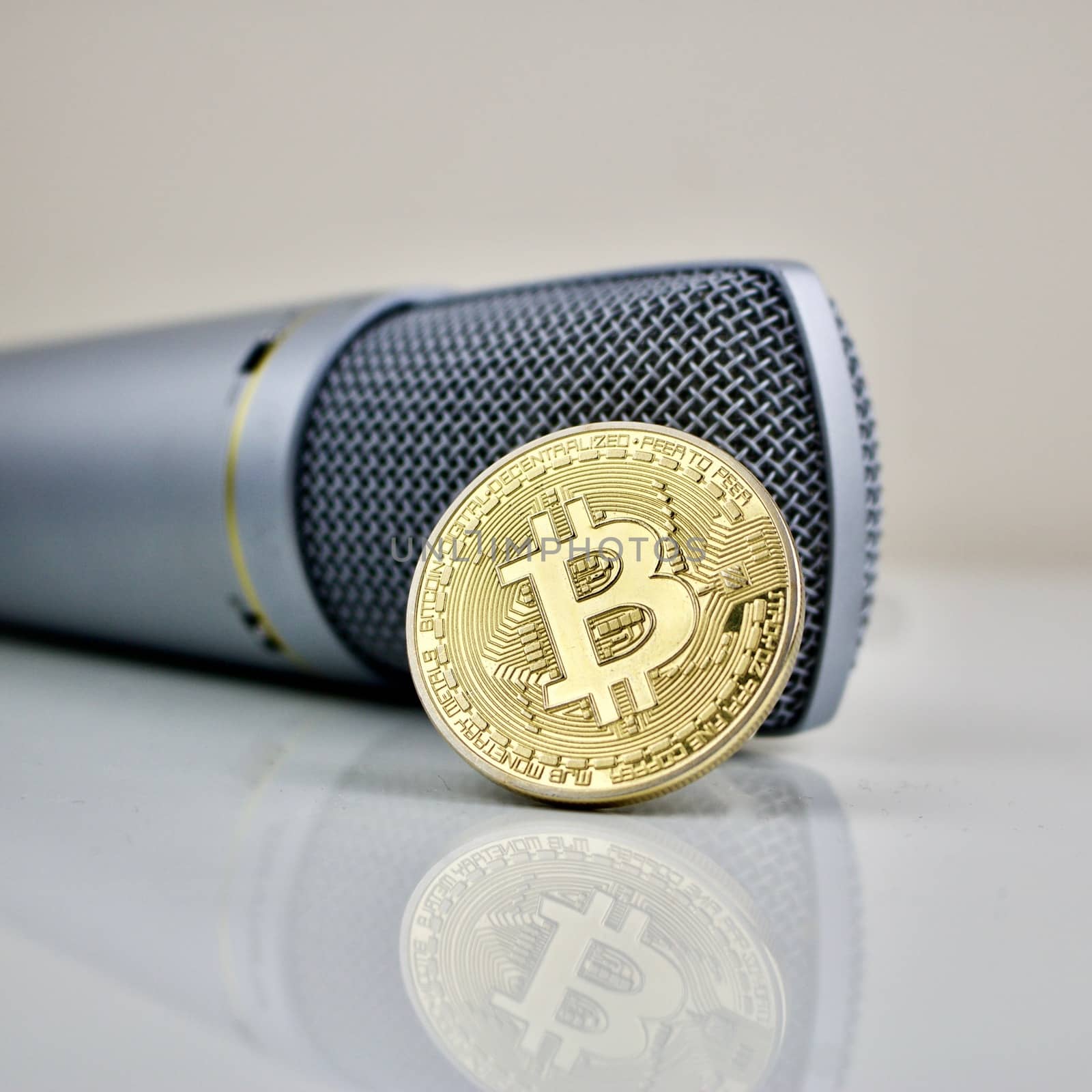 Gold bitcoin cryptocurrency coin and silver microphone.