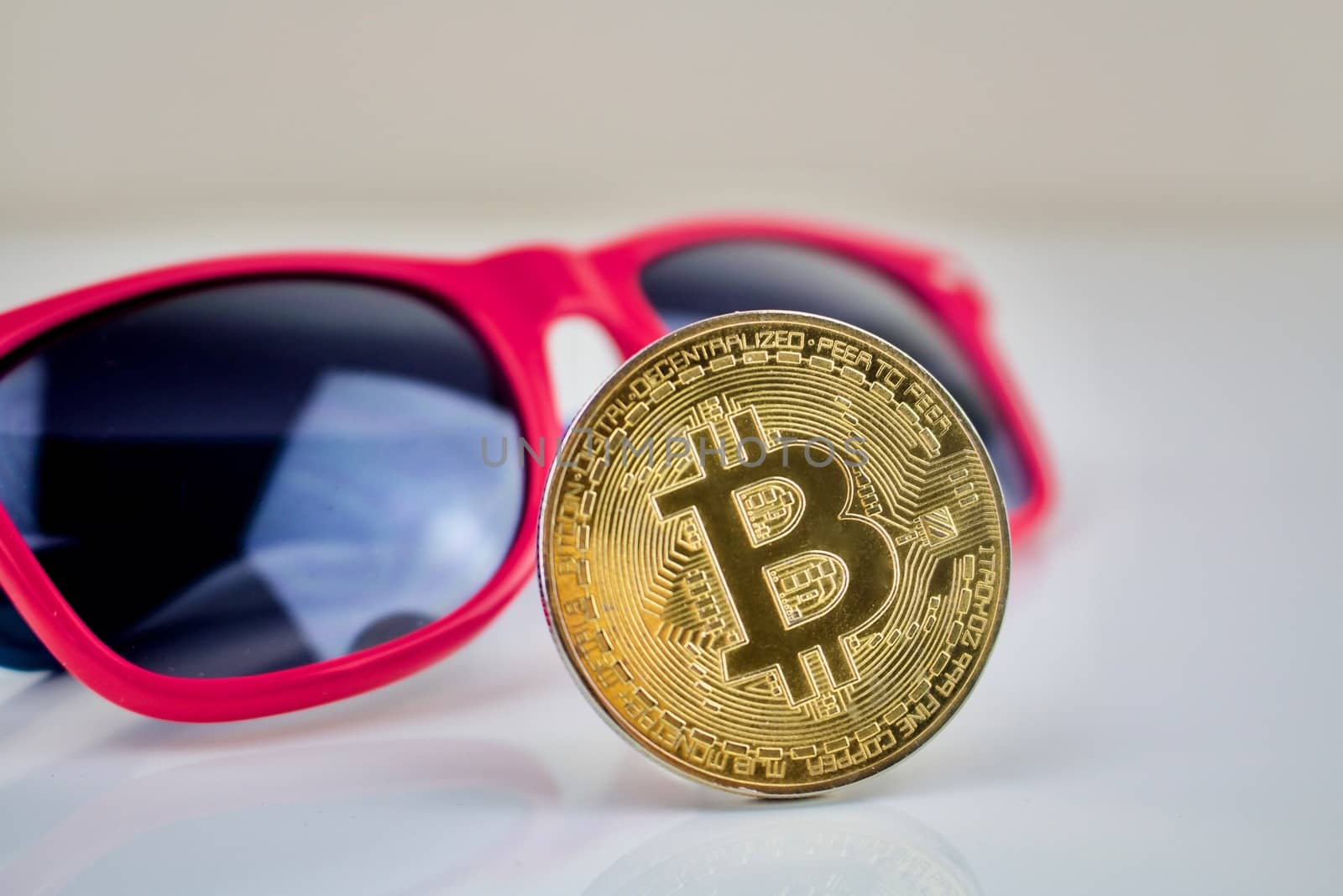 Cryptocurrency physical gold bitcoin coin and pink sunglasses