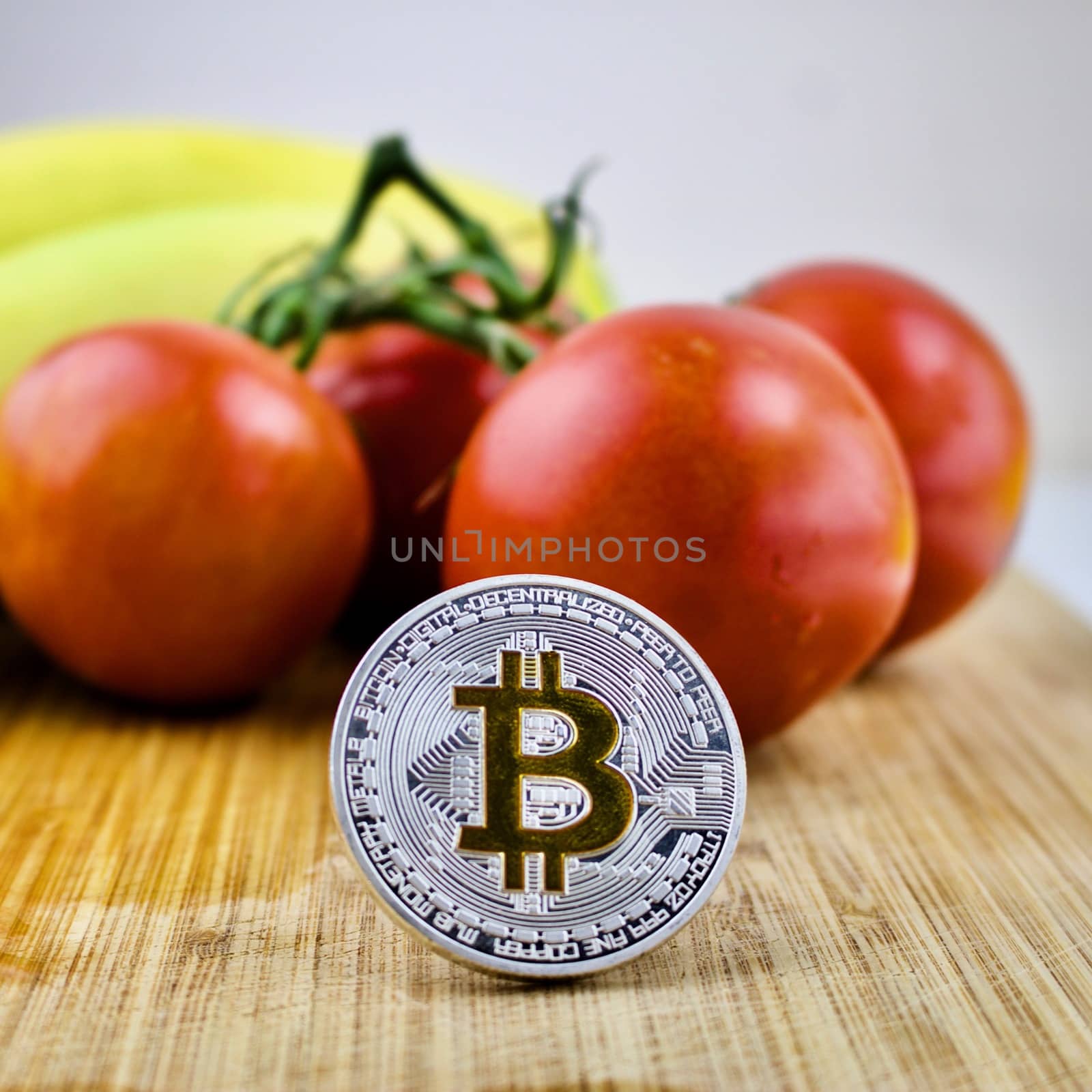 Cryptocurrency silver bitcoin coin, tomatoes and bananas