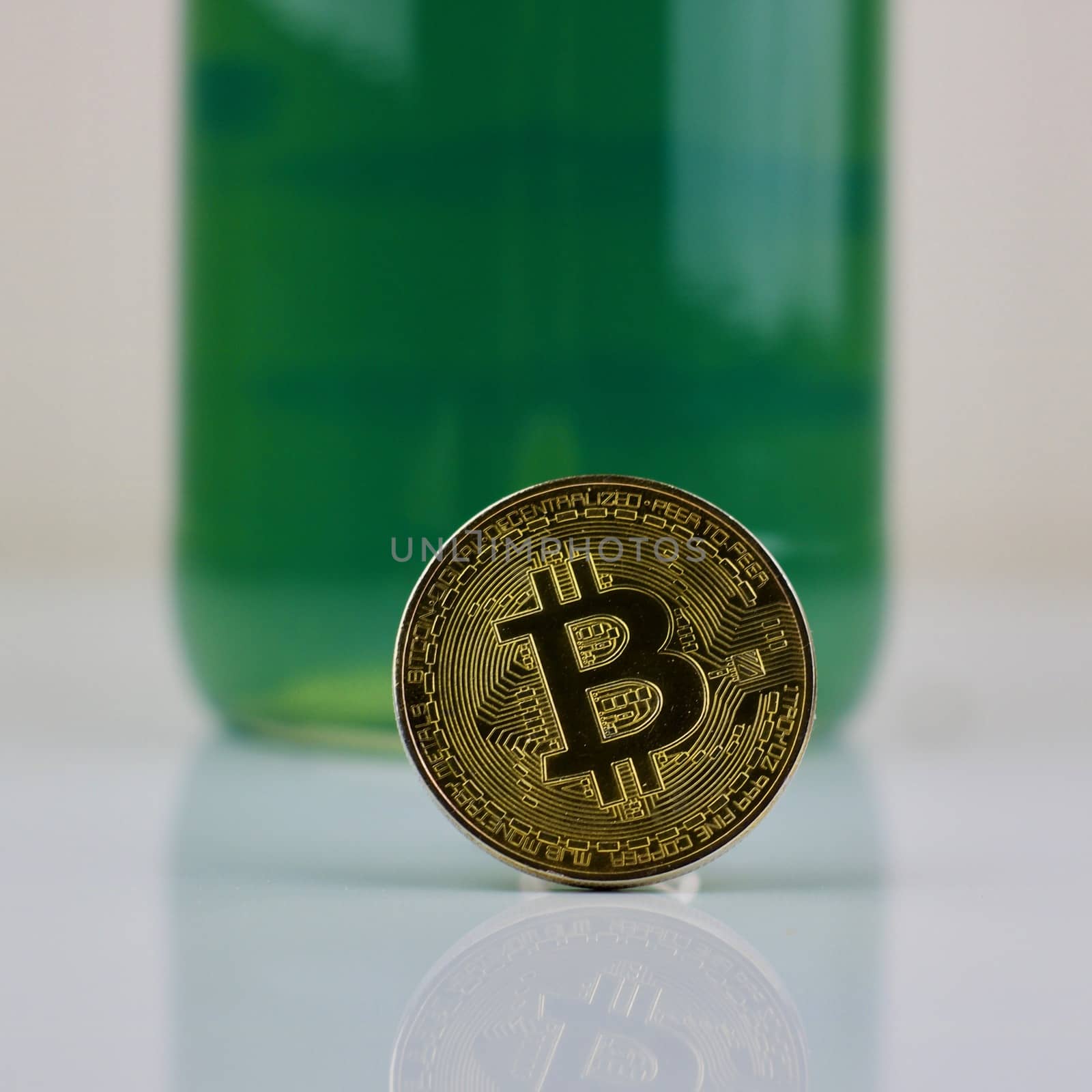 Cryptocurrency physical gold bitcoin coin and green bottle.