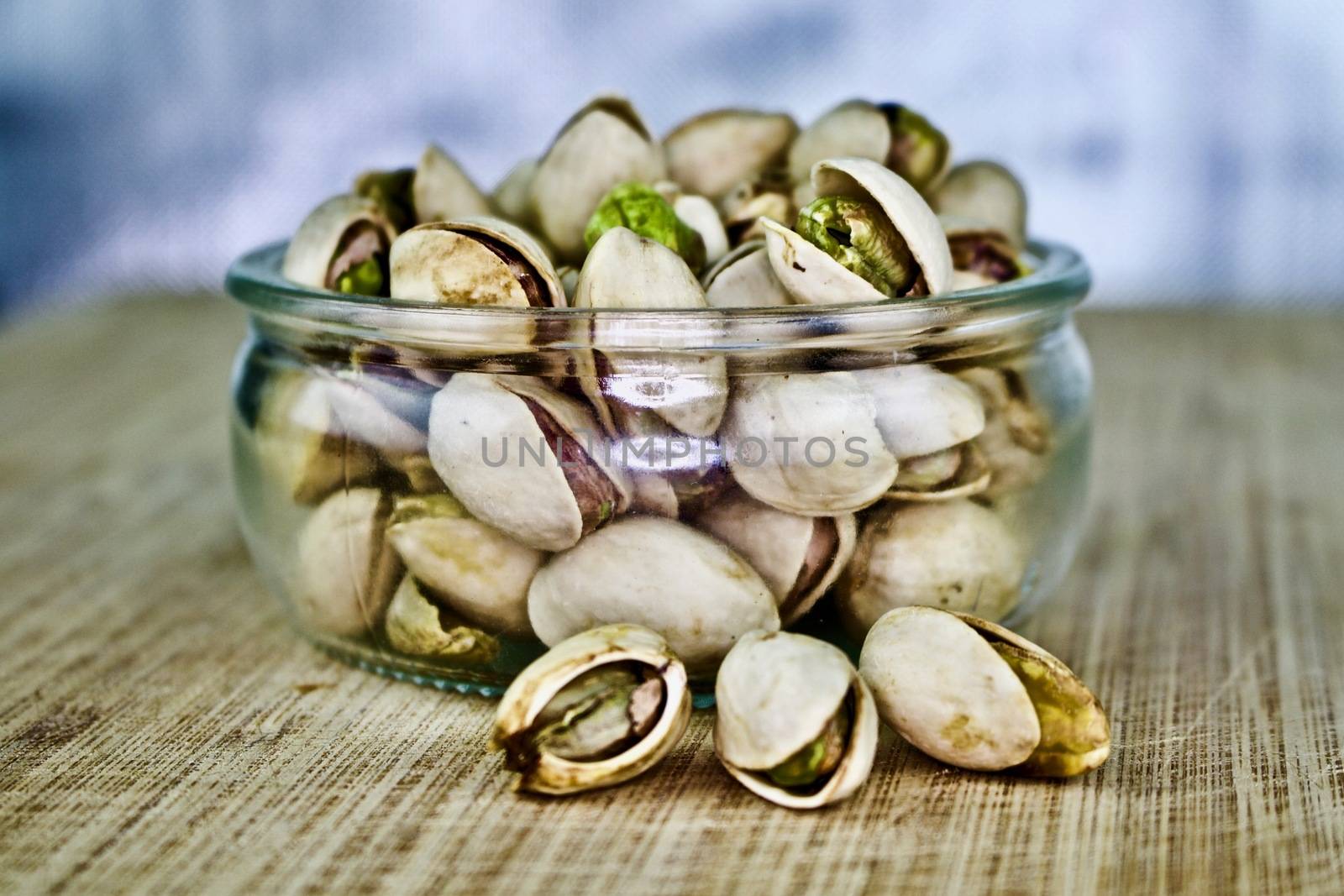 Pistachios nuts in small glass on the wooden old board