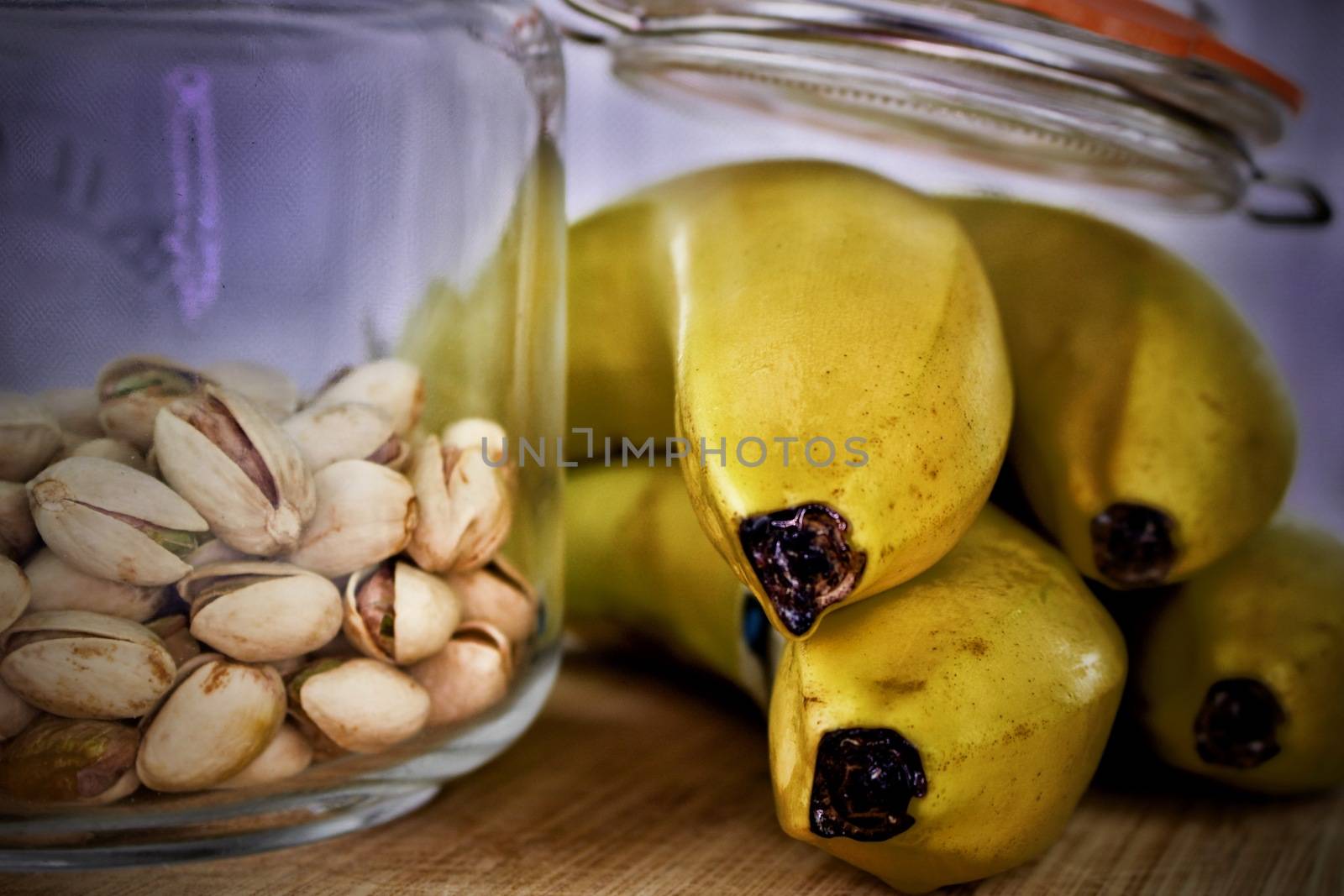Pistachios in jar and yellow bananas on the wooden board