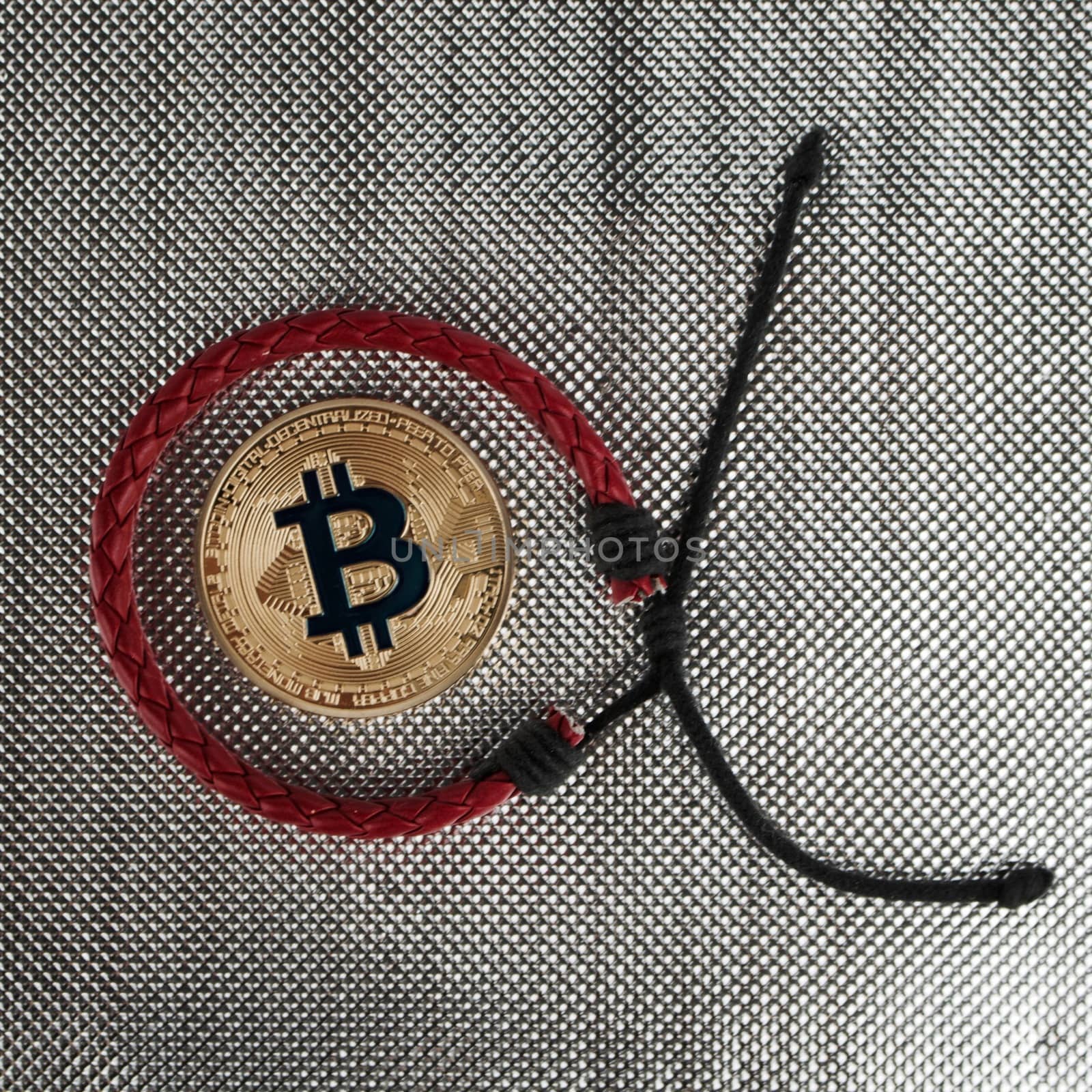 Digital currency physical gold bitcoin coin near red bracelet
