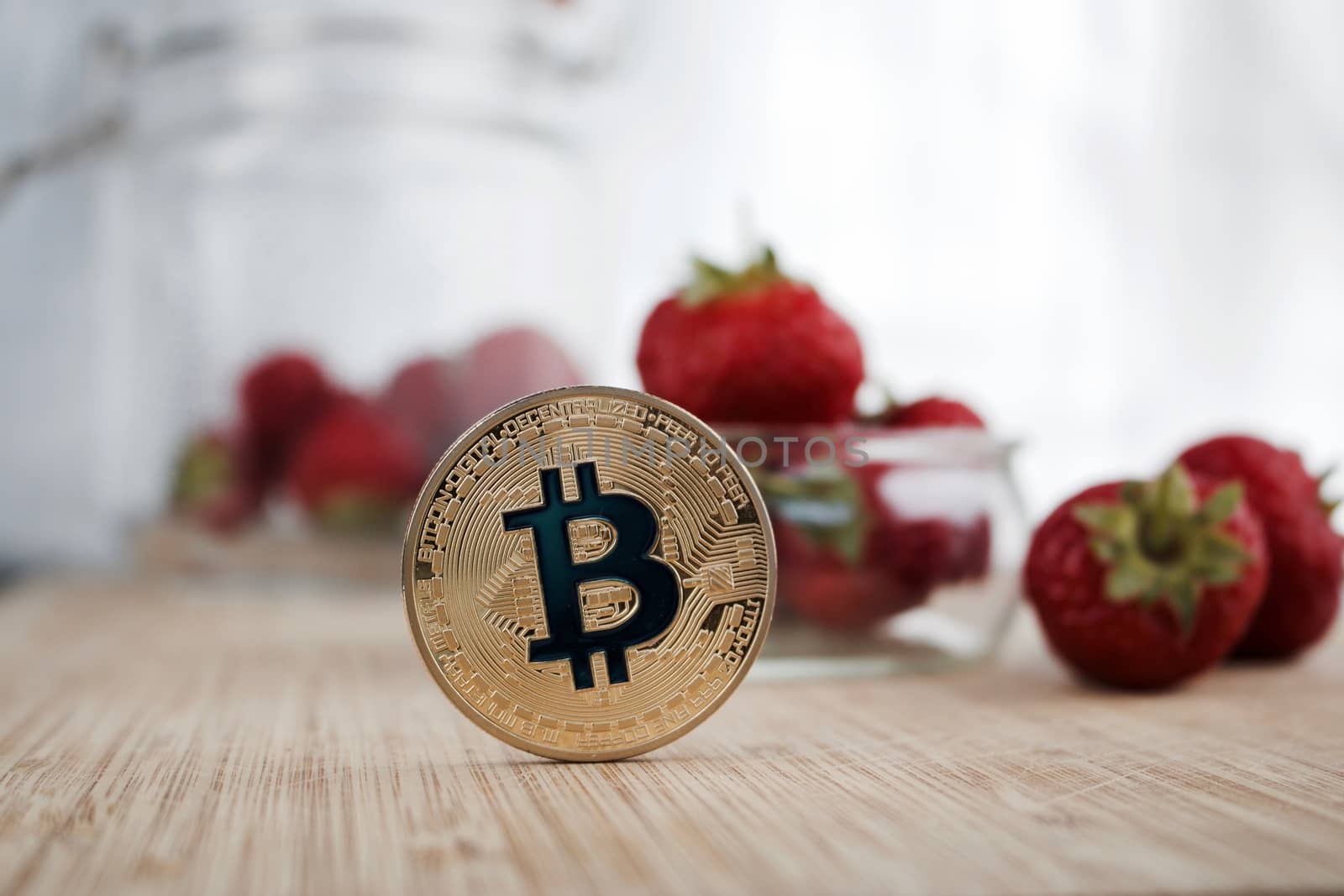 Cryptocurrency physical gold bitcoin coin near strawberries.