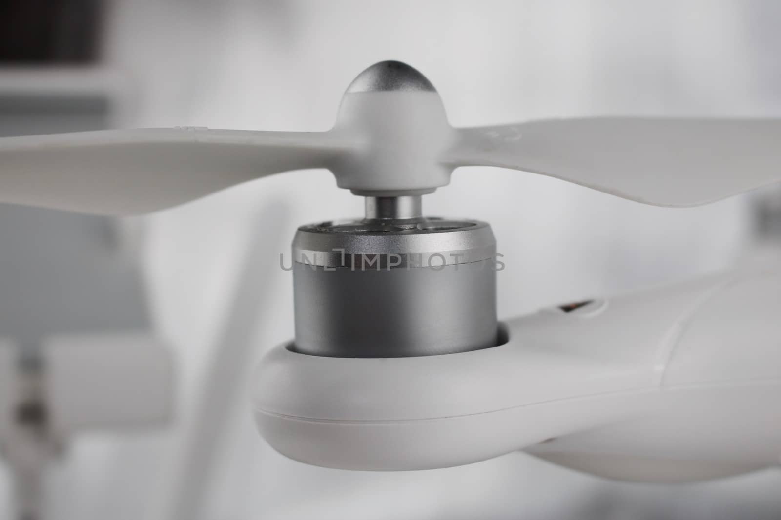 White drone arm with silver small engine and air screw on the top.