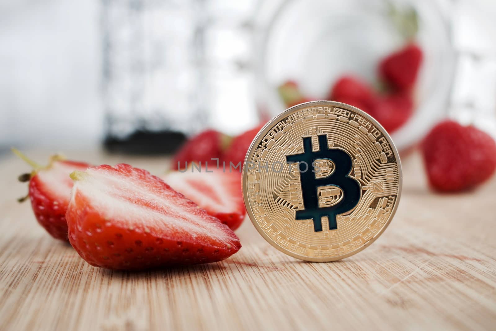 Digital currency physical gold bitcoin coin near fresh strawberries