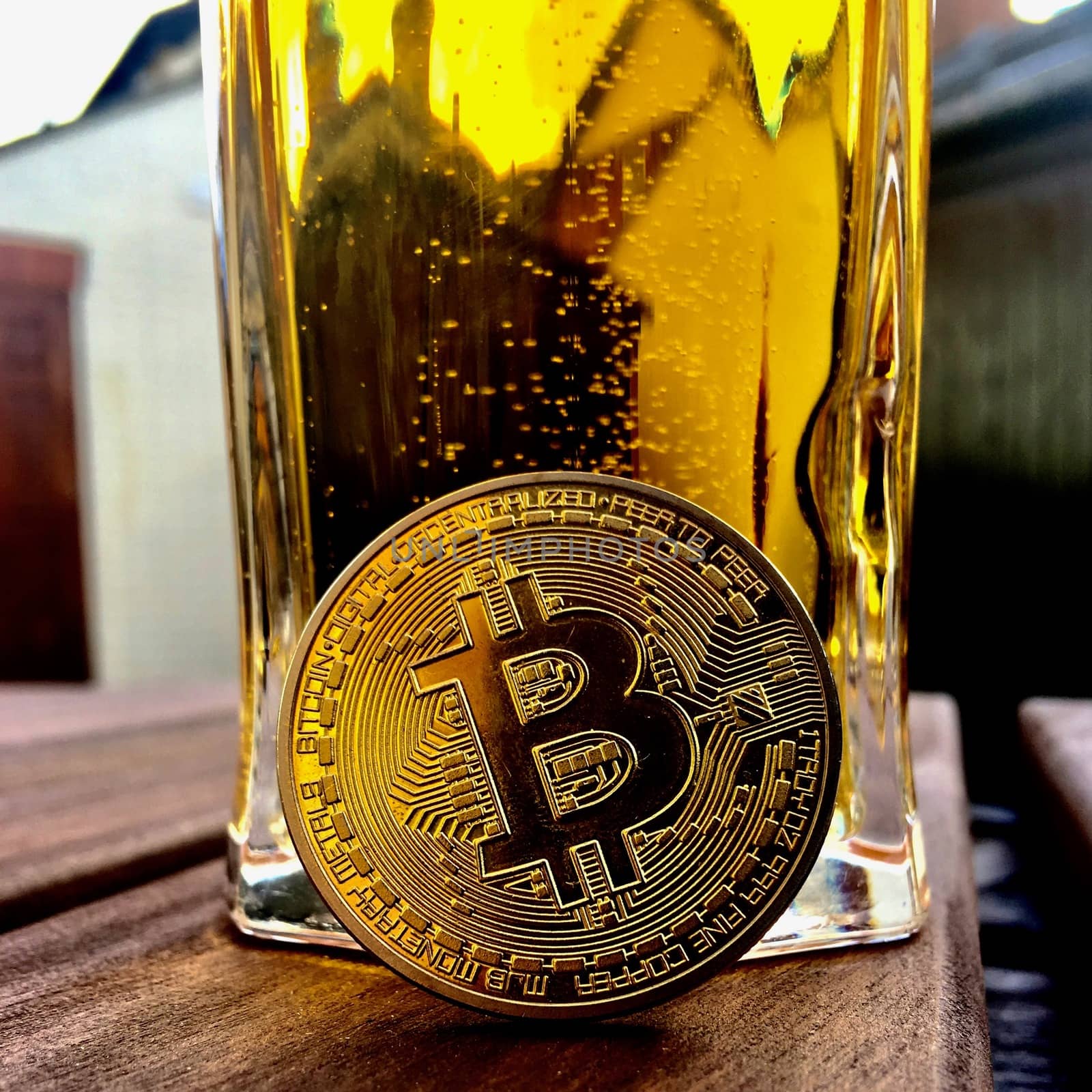 Cryptocurrency physical brass bitcoin coin and beer in glass
