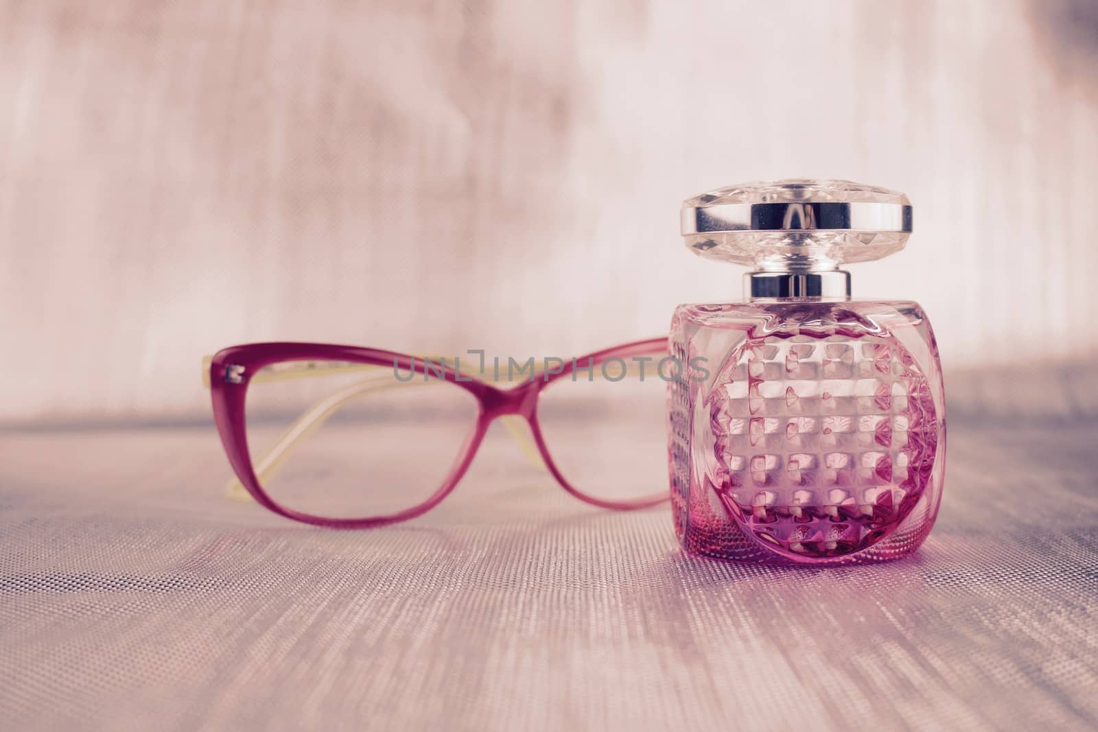 Small fragrance bottle near pink glasses concept