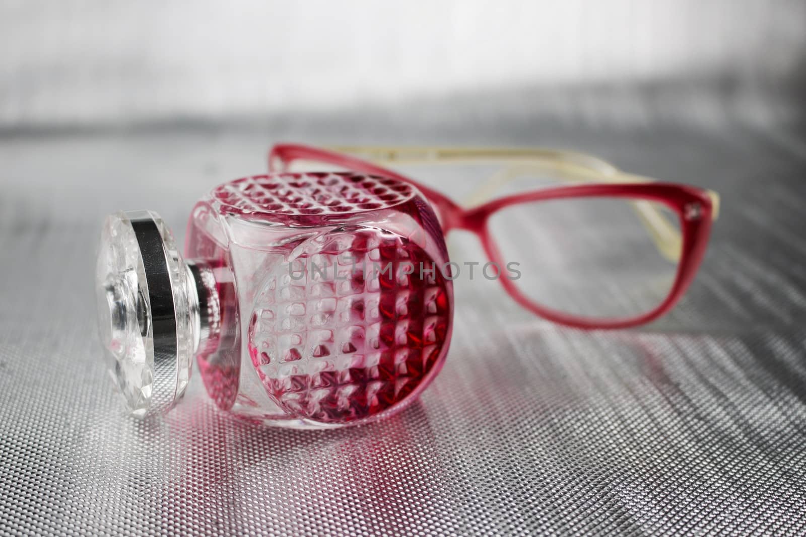 Pink bottle with a perfume and pink female glasses