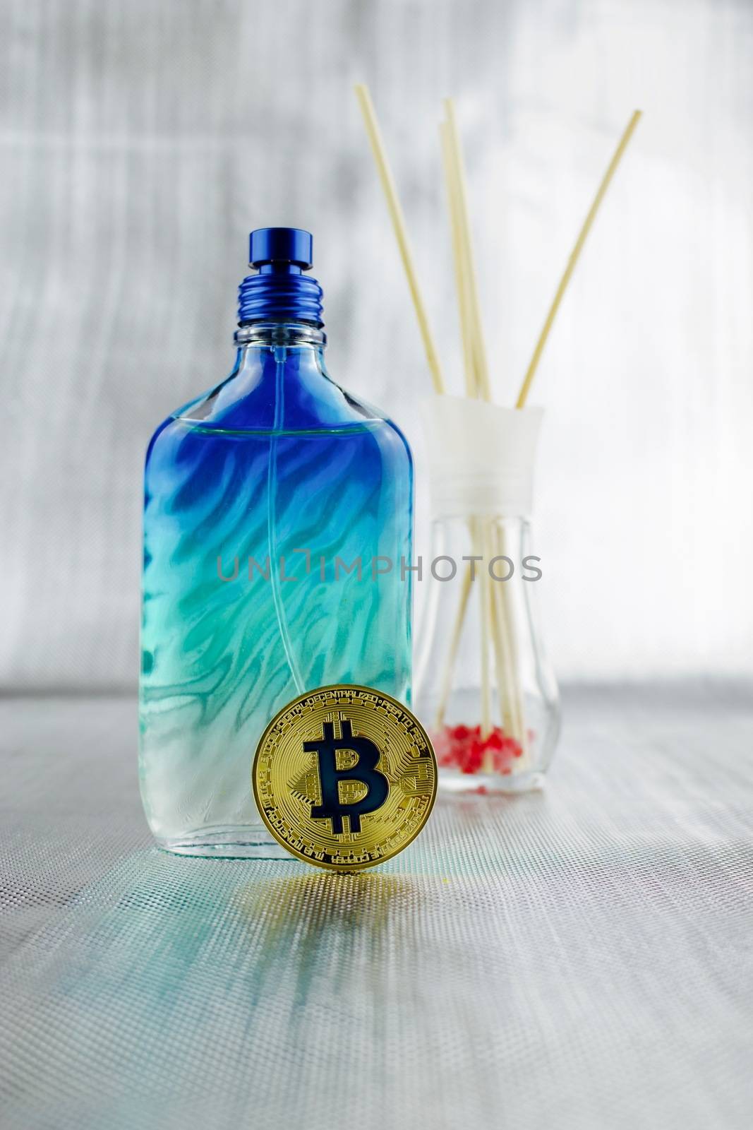 Cryptocurrency physical gold bitcoin coin near fragrance in blue bottle