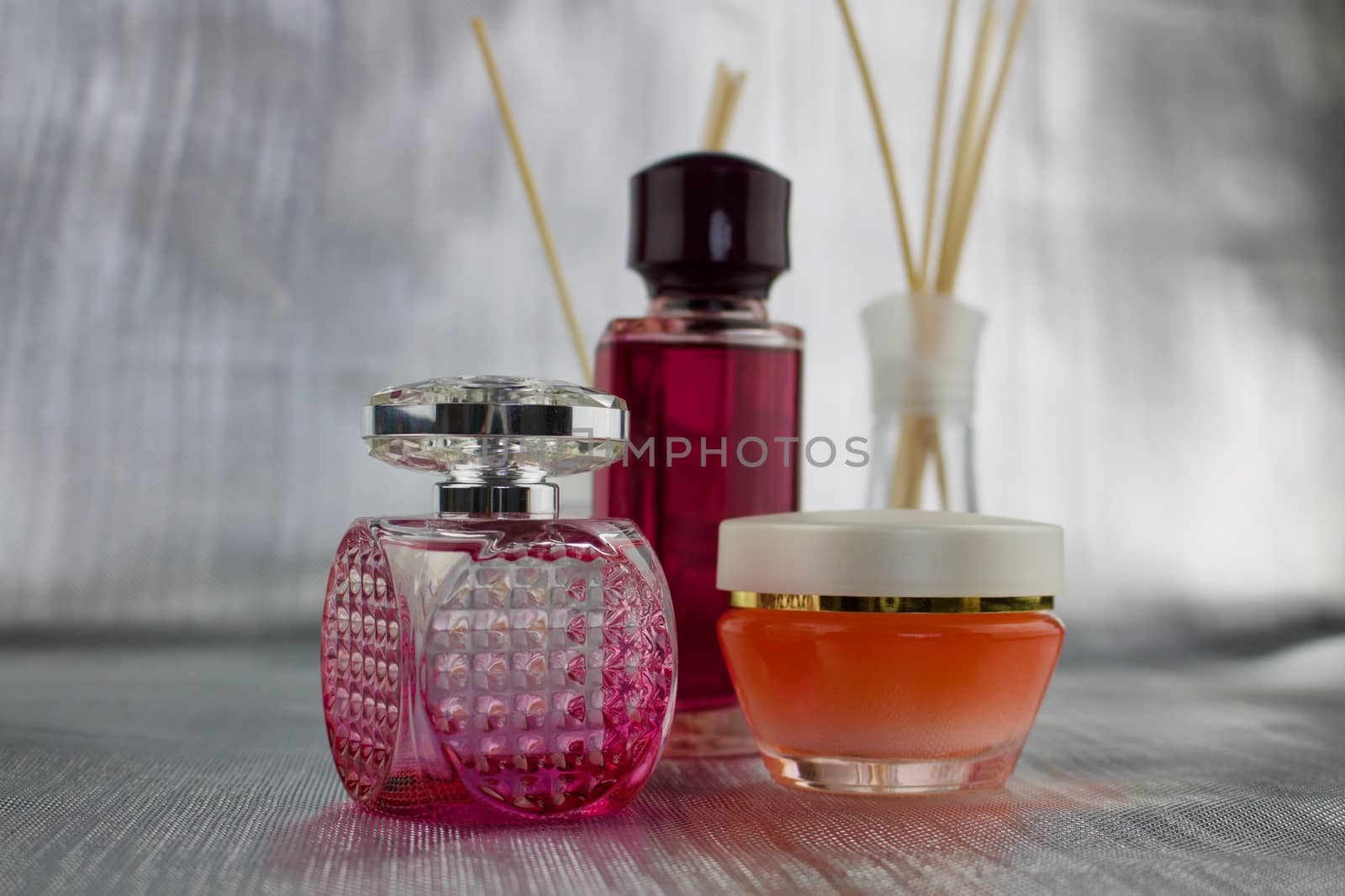 Pink perfume two bottles and orange creme on the table