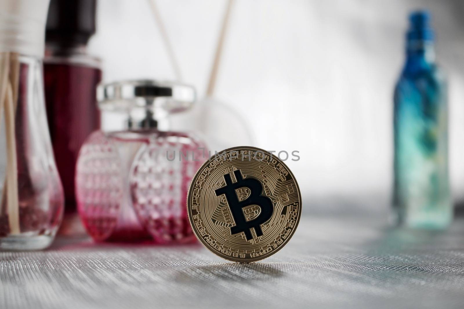 Digital currency physical gold bitcoin coin in pink perfume composition.