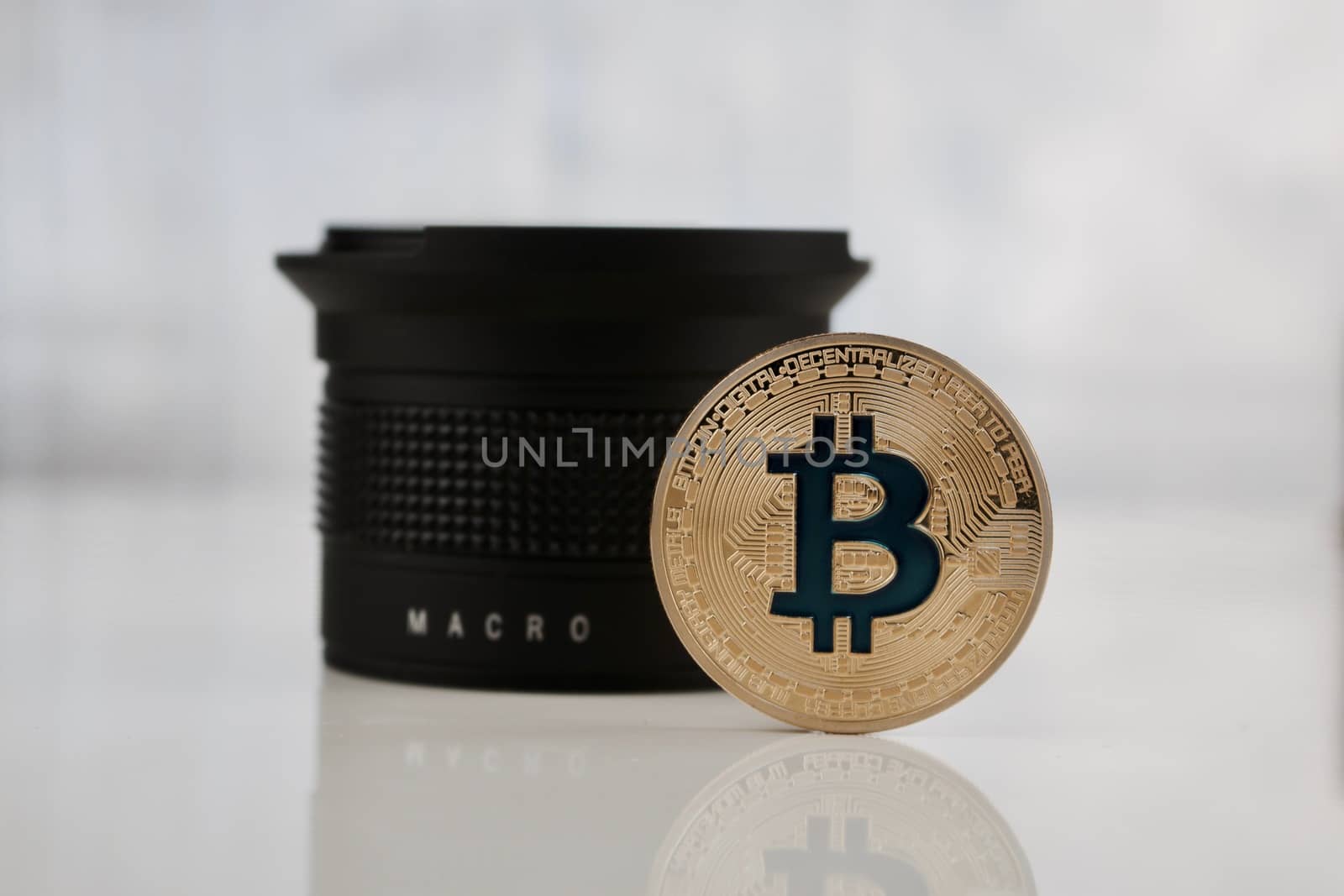Cryptocurrency physical gold bitcoin coin with blue sign near macro lens.