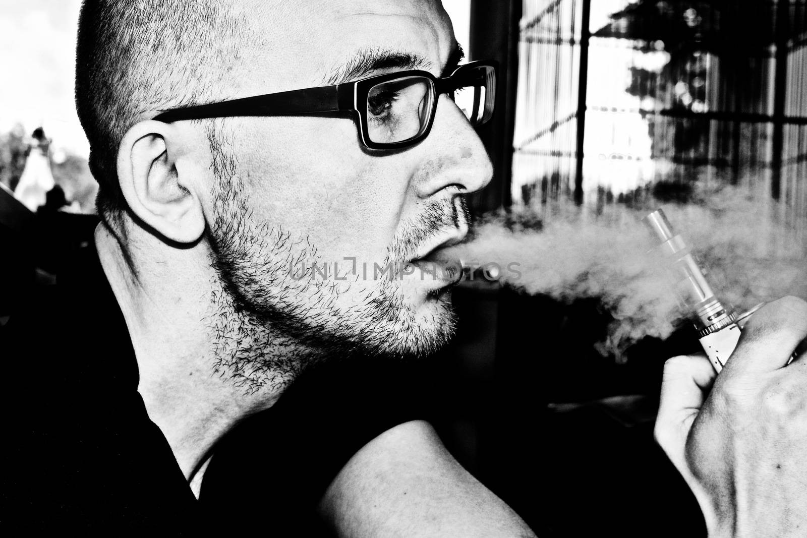 Young man in black glasses smoking electronic cigarette