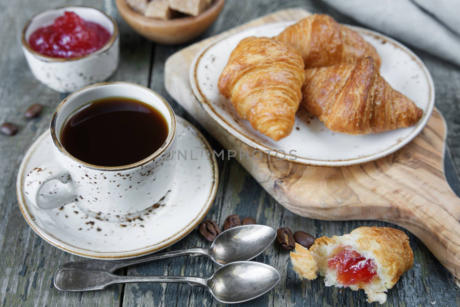 Light breakfast consisting of a cup of black coffee and croissants with a stuffing from raspberry jam