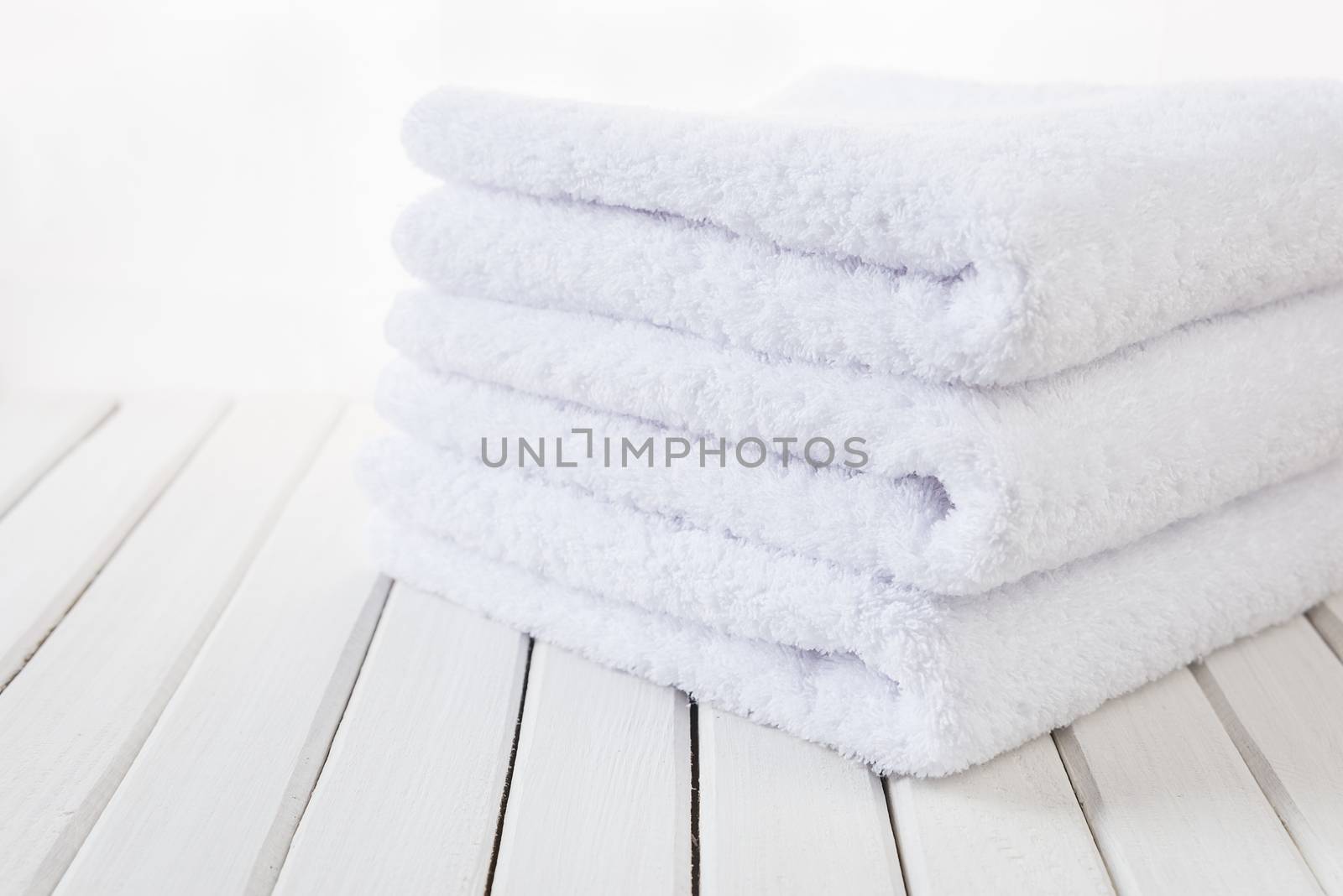 Stack of three white fluffy bath towels on the background of white boards