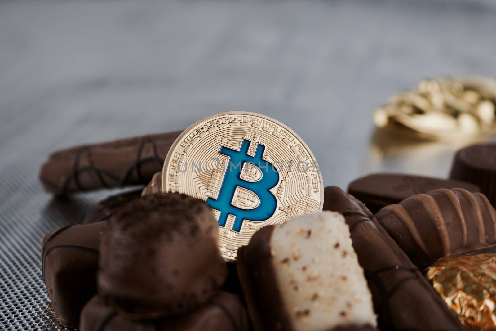 Digital currency physical blue bitcoin coin and chocolates.