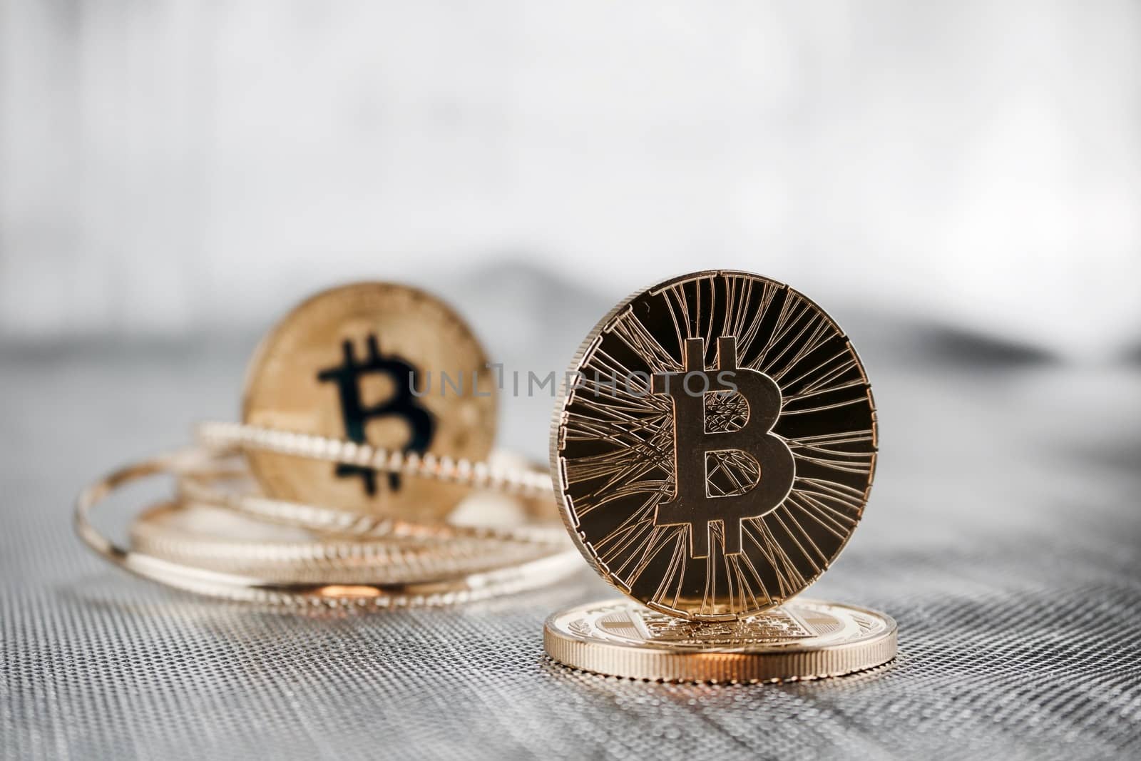 Digital currency physical gold bitcoin coins. Silver background.