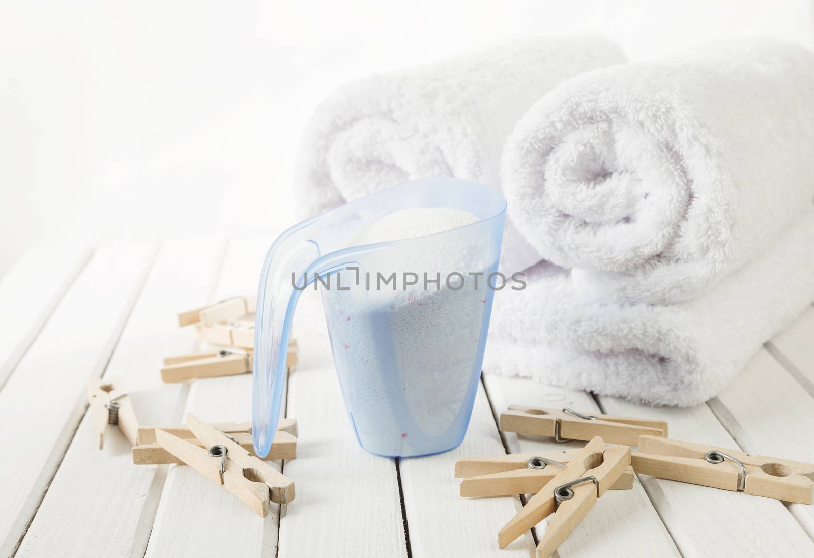 Bath towels, washing powder in measuring cup and wooden clothesp by Epitavi