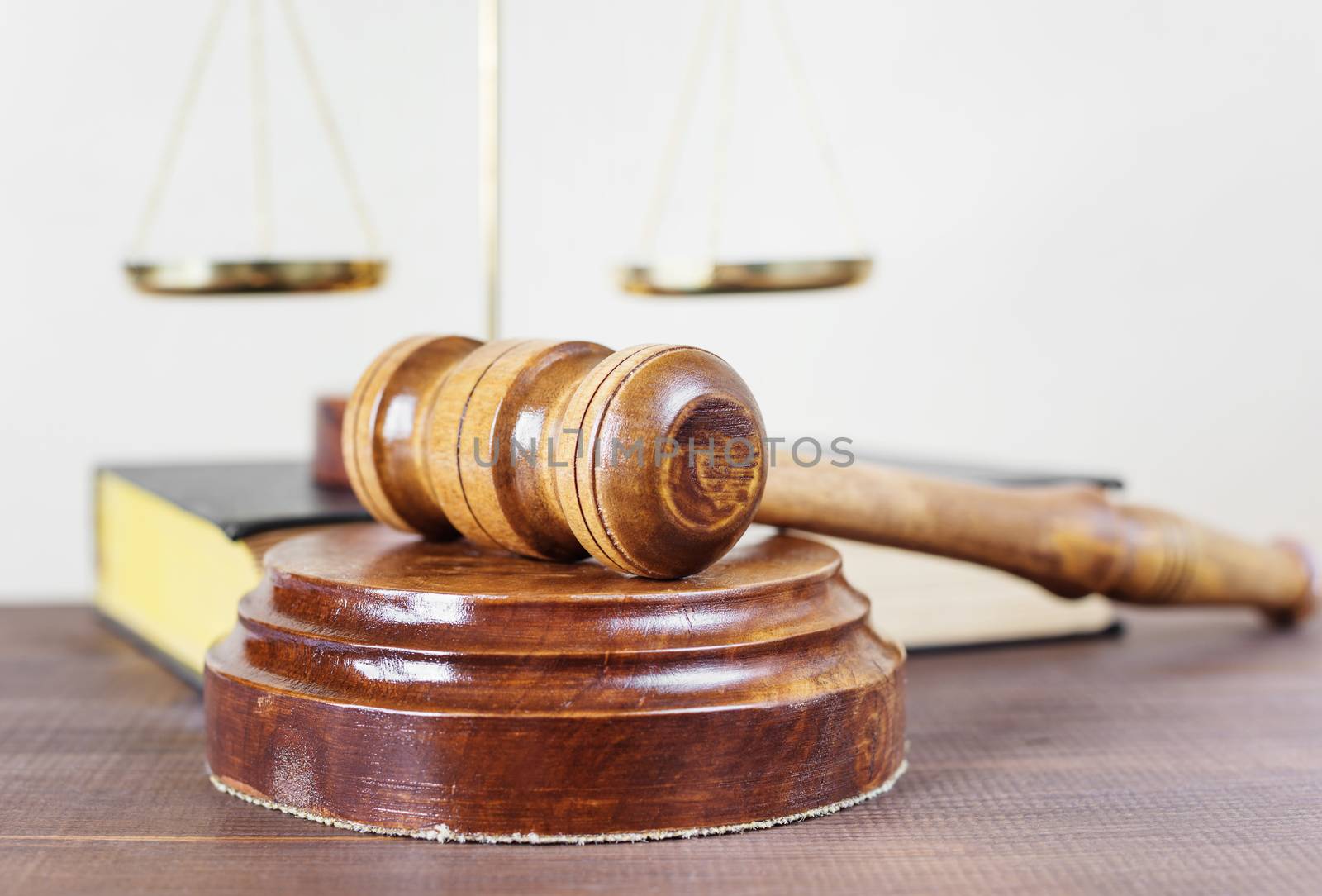 Symbols of law: wood gavel, soundblock, scales and volumetric book on a wooden table