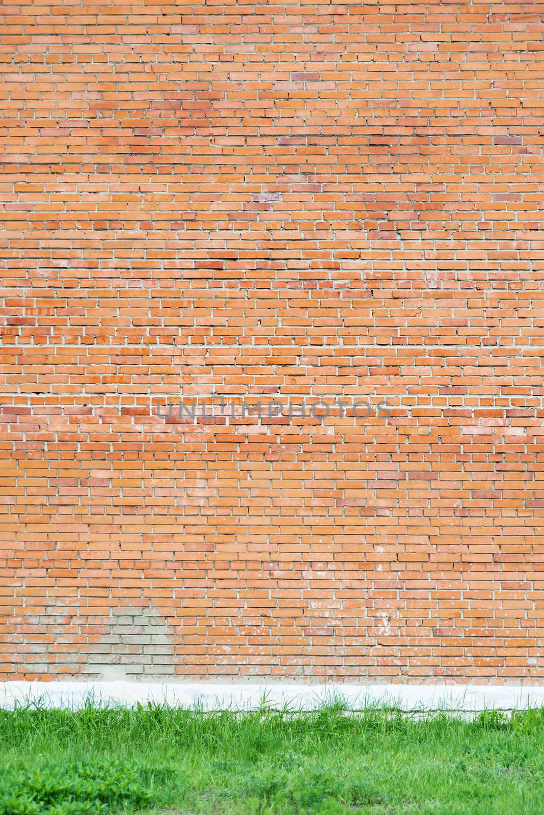 Large wall of red brick with a border of green grass