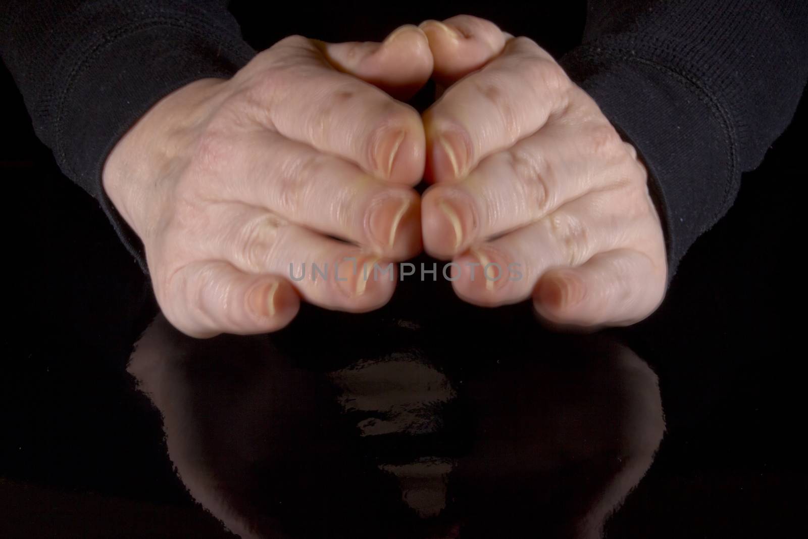 Female hands and their reflection on a black background