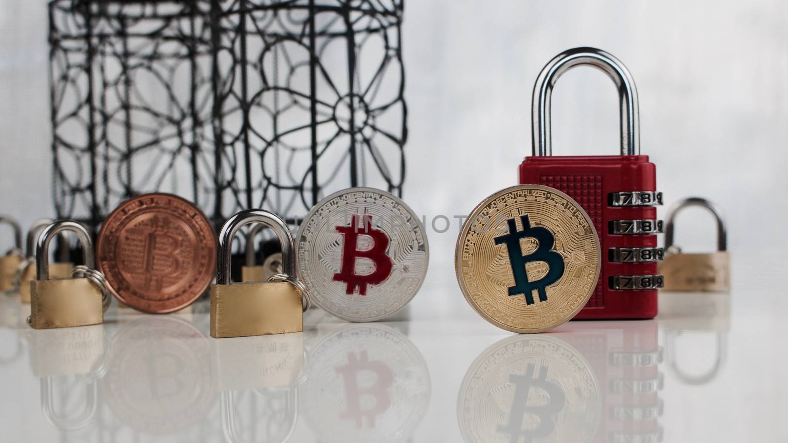 Digital currency physical brass, silver and gold bitcoin coins near padlocks.