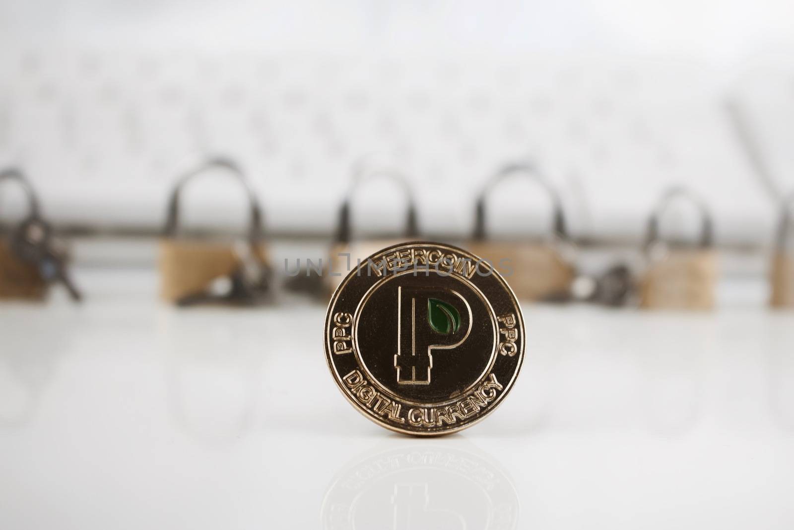 Cryptocurrency physical gold peercoin coin near gold padlocks and keyboard.