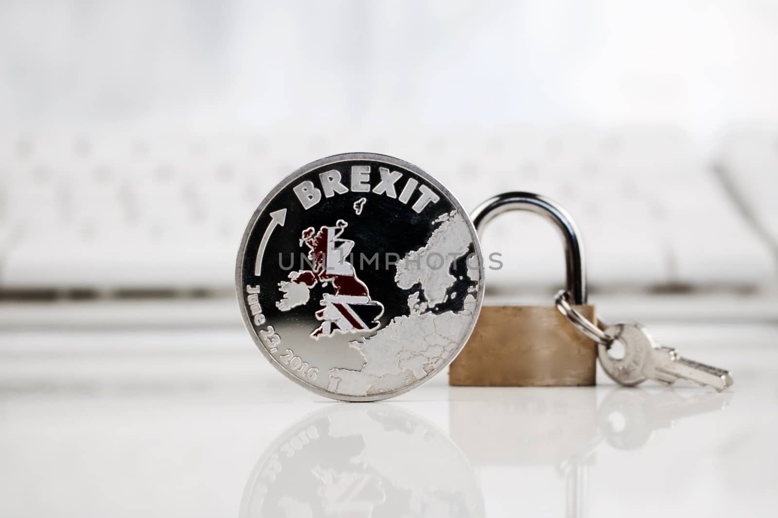 Physical silver brexit coin near gold padlock.