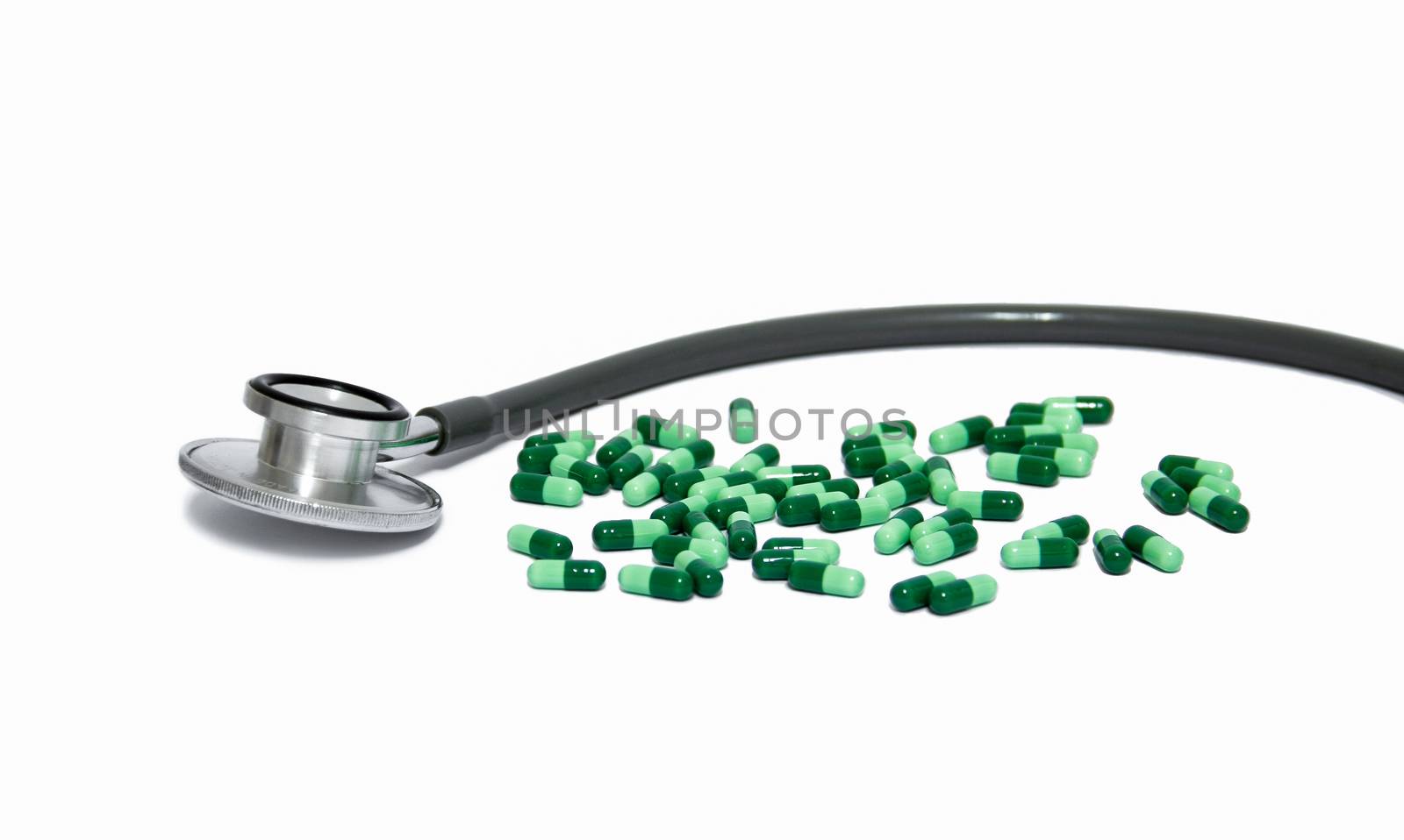 head of stethoscope and green capsule medicine on white background