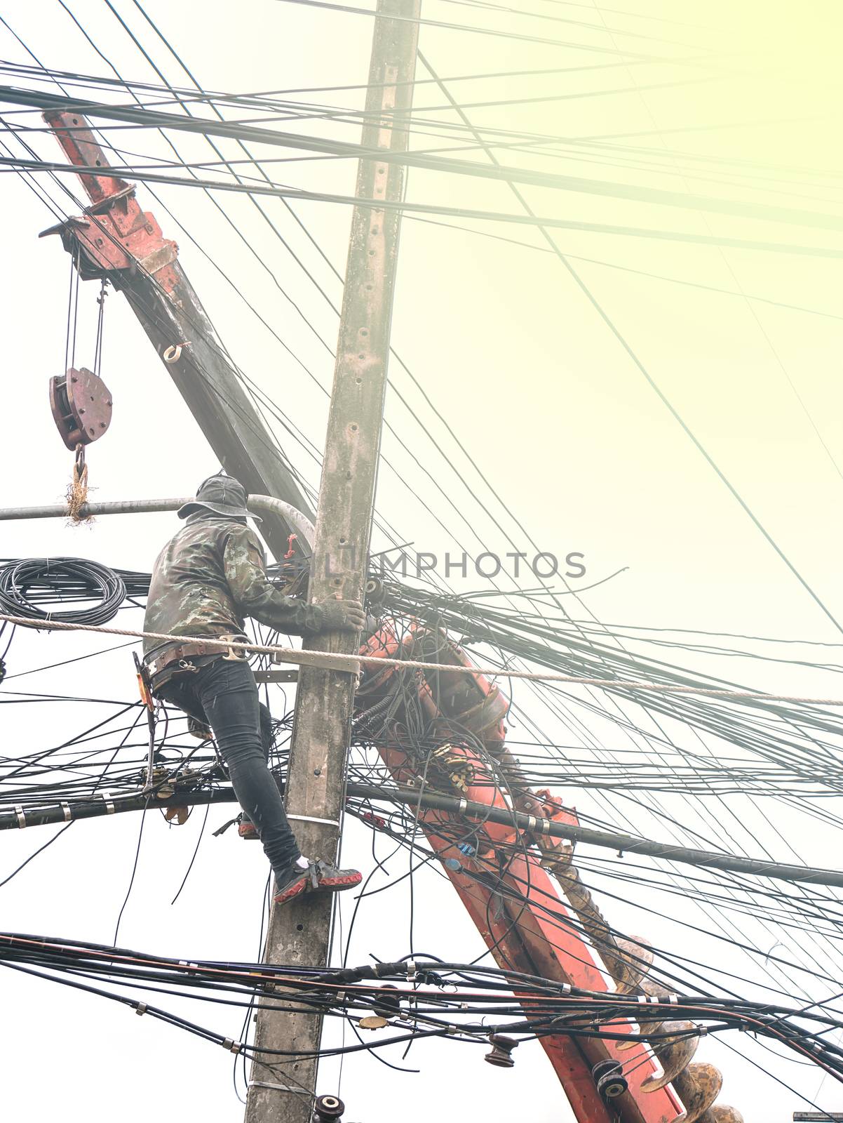 Repair workers are swinging on cable posts to fix the line of network cable and wire on electric pole in Thailand