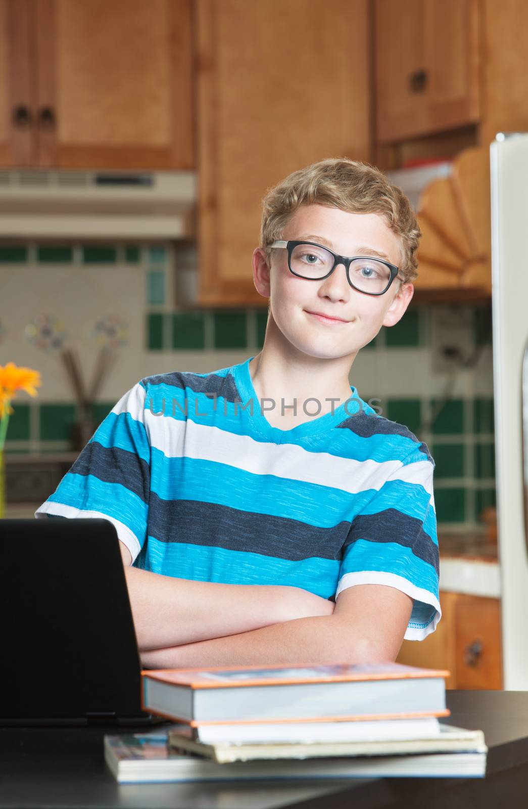 Single confident teenage male student in kitchen with textbooks