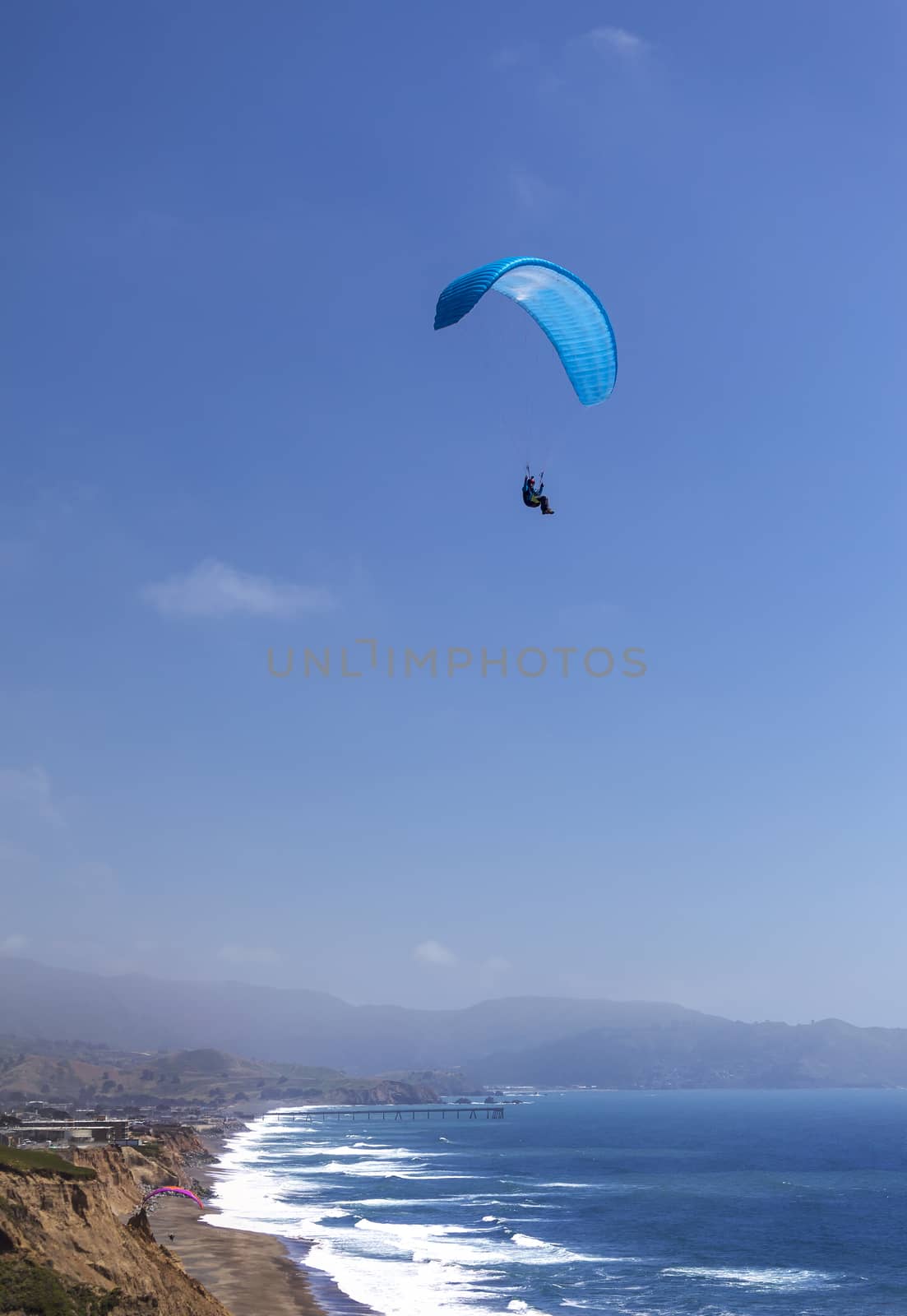 This is an image of a paraglider over Muscle Beach along California’s central coast.  Muscle beach is located in Pacifica, California, which is a prime spot for paragliding due to its fantastic weather conditions and views. 