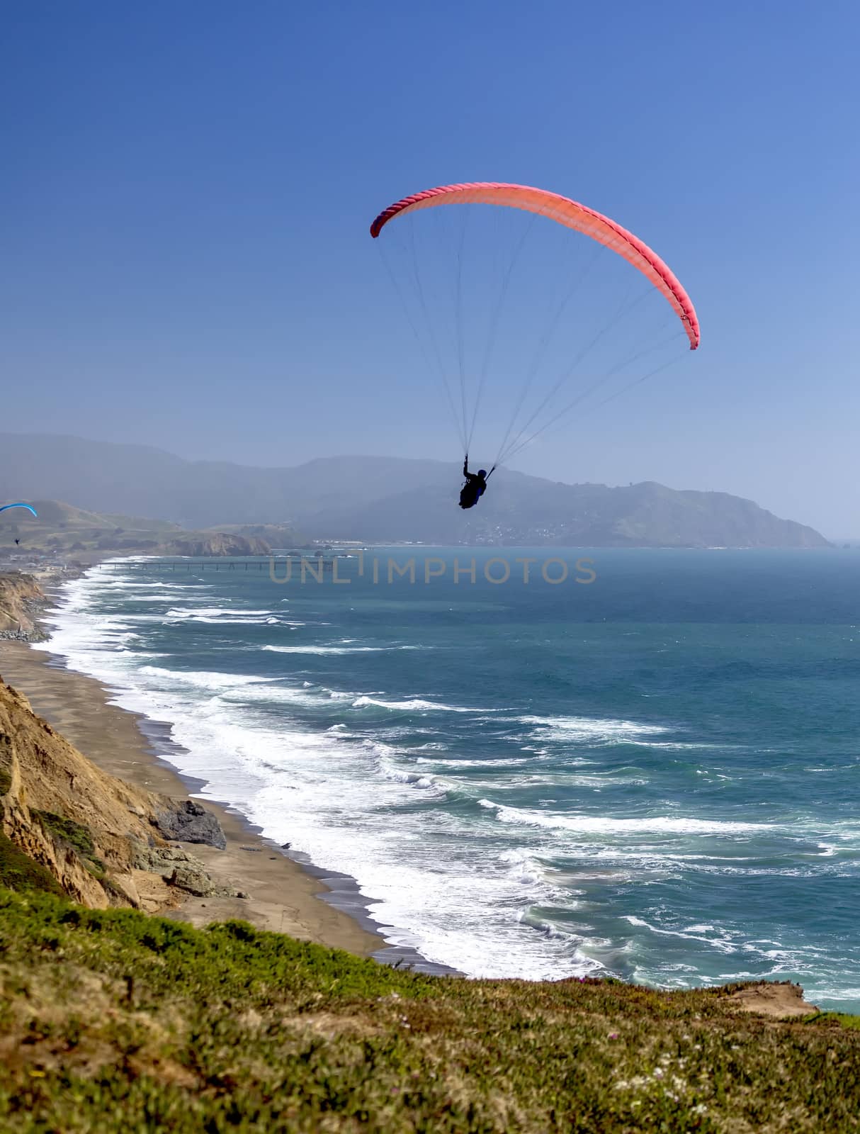 This is an image of a paraglider over Muscle Beach along California’s central coast.  Muscle beach is located in Pacifica, California, which is a prime spot for paragliding due to its fantastic weather conditions and views. 