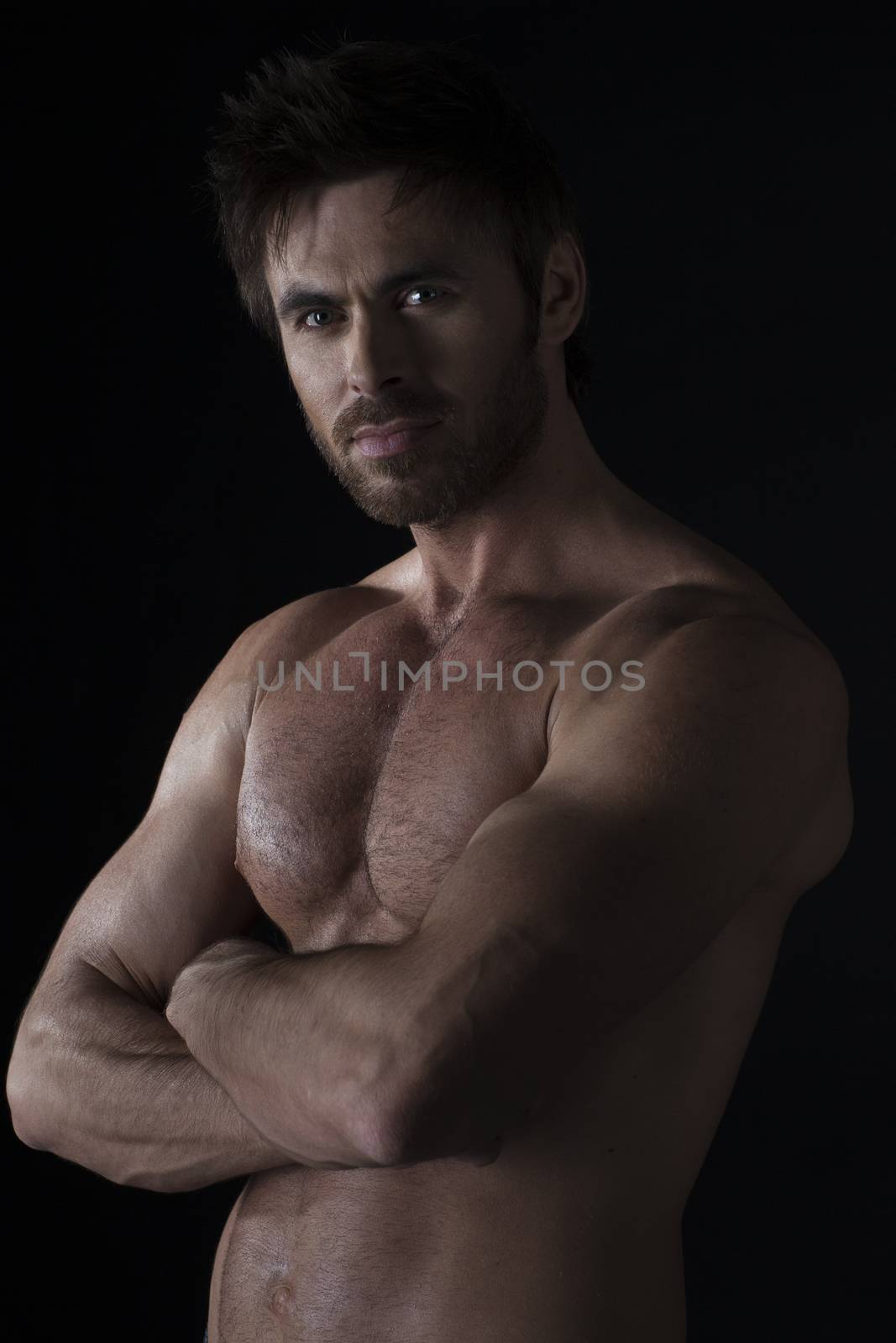 Dark shot of healthy muscular naked young man with crossed hands