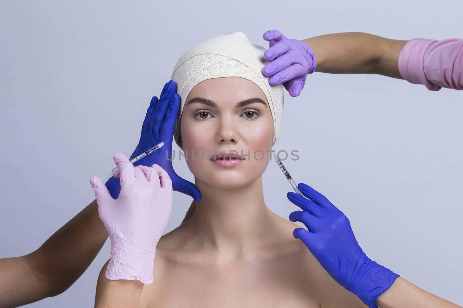 Attractive young woman gets cosmetic injection. Doctors hands making an injection in face. Beauty Treatment.